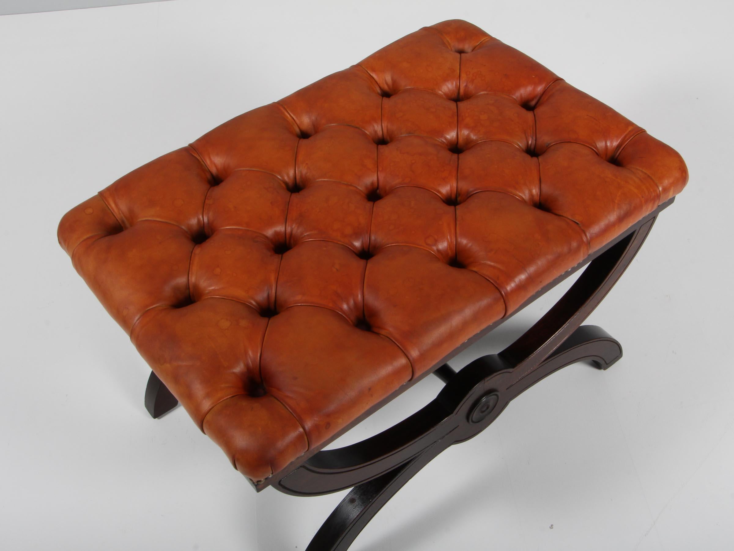 Danish cabinetmaker ottoman of patinated nature leather, with buttons. 

Legs of mahogany with profilated details.

Made in the 1930-1940s.