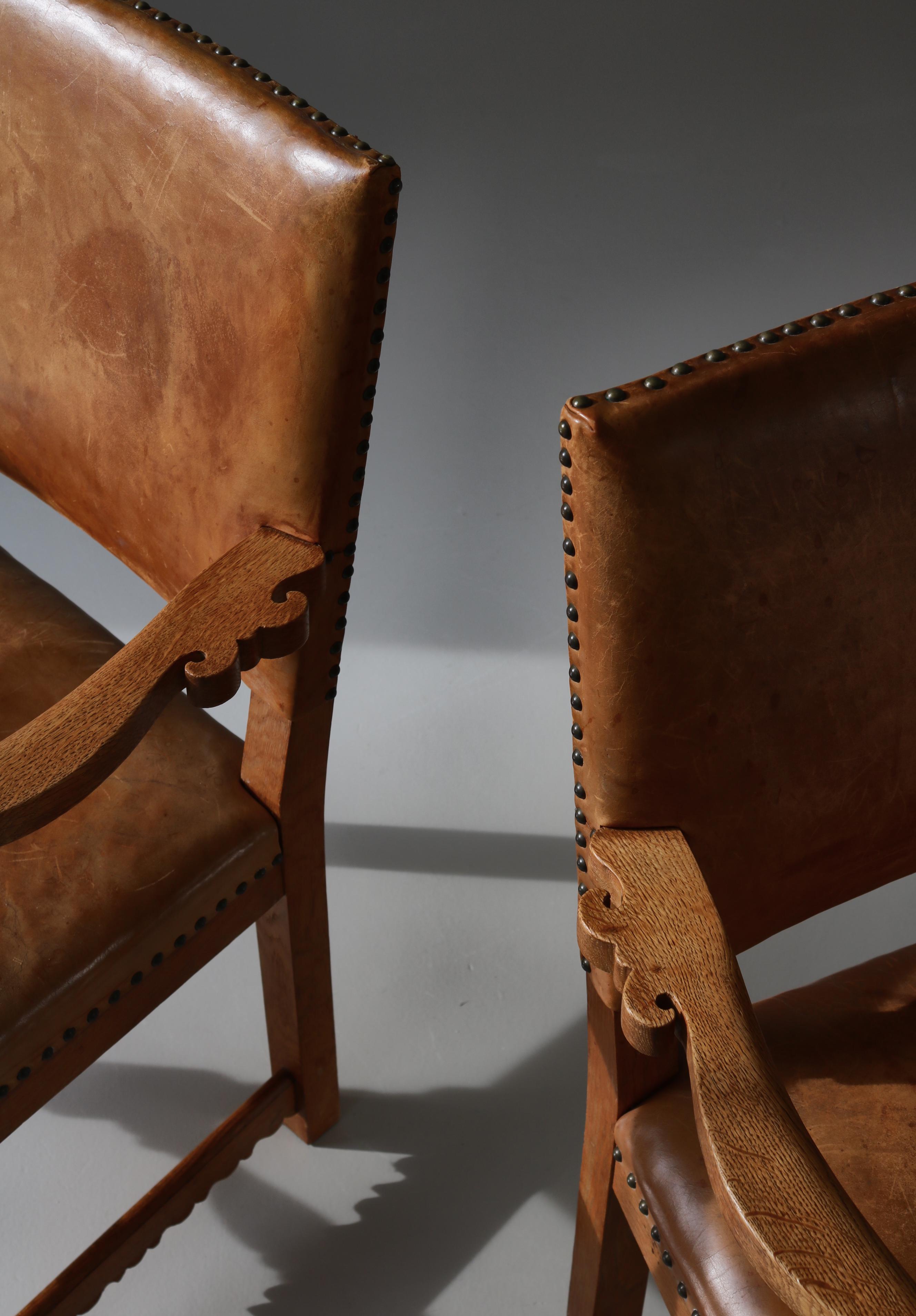 Stunning pair of sculptural armchairs in solid oak and natural leather made by Danish Master Cabinetmaker Lars Møller, Copenhagen in the 1930s. The chairs are modern but with a playful expression and many fine details like the skilfully carved