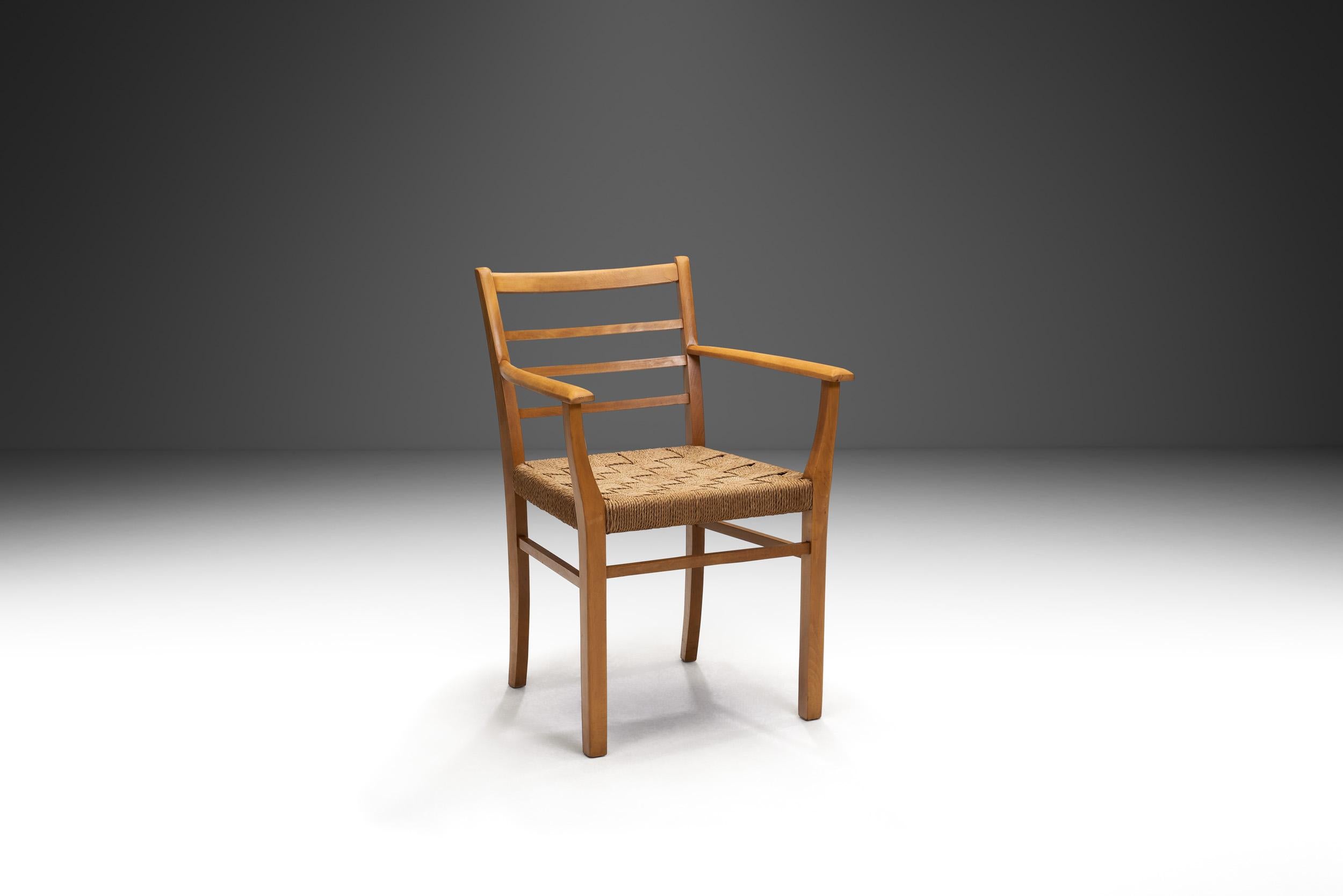 En el diseño danés de mediados de siglo, la elegancia atemporal y la artesanía dominaban la época, combinadas con el uso de materiales orgánicos como la madera y la cuerda de papel. Fabricado con los cálidos tonos marrones de la madera, este sillón