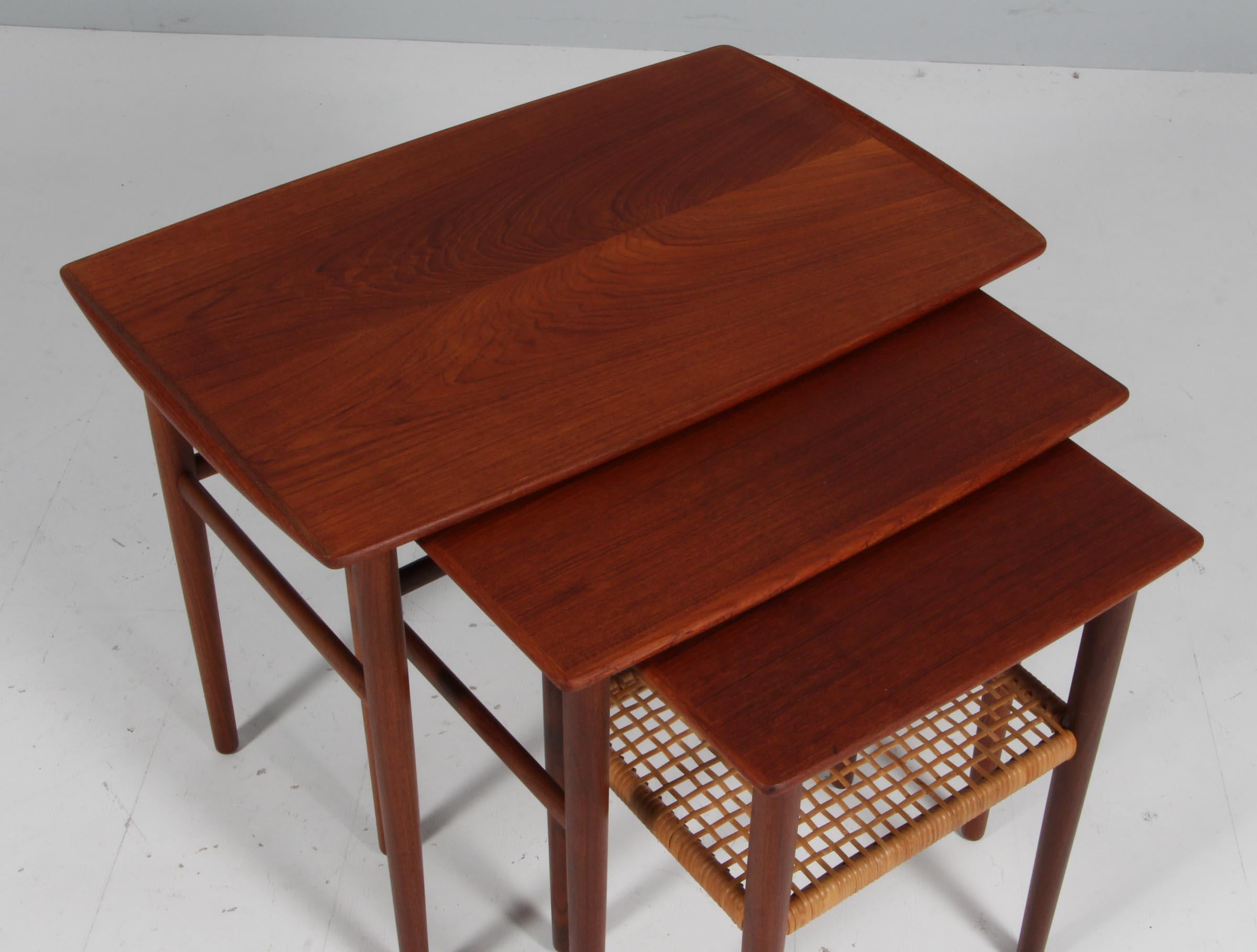 Set of nesting tables made in partly solid teak with curved edges. With shelf of cane.