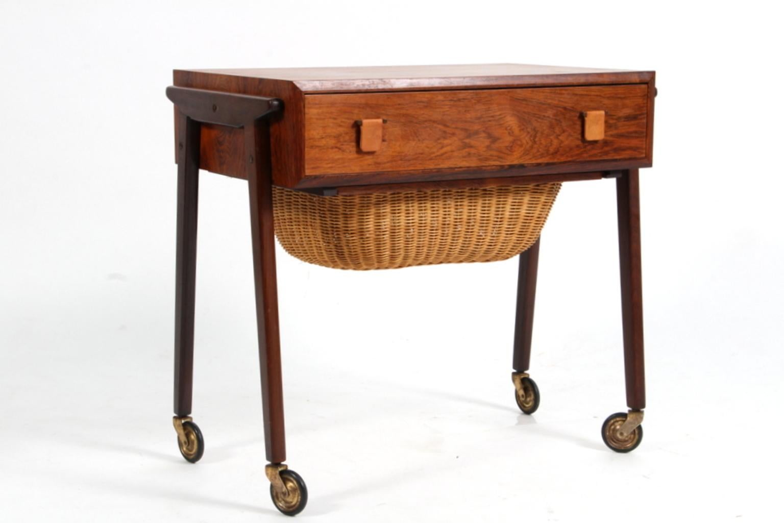 Danish cabinetmaker sewing table in rosewood. Handles of butt leather. Two drawers, one in wicker.

On wheels.