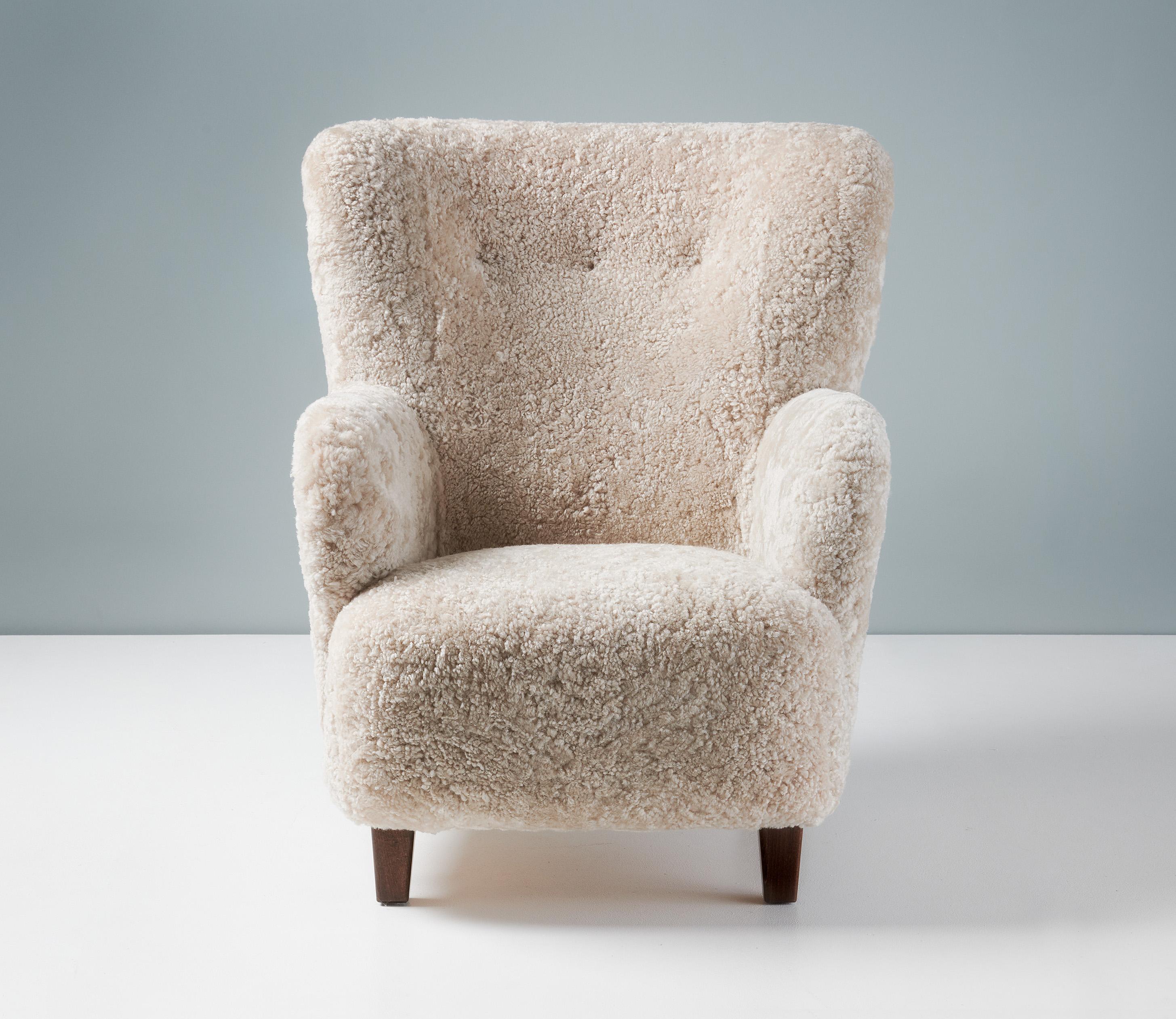 Danish Cabinetmaker Sheepskin Armchair, circa 1940s.

This tall lounge chair produced by a Danish Cabinetmaker in the 1940s is typical of Danish lounge chair designs of the day. It features a slightly curved wing-back with round arms and stained
