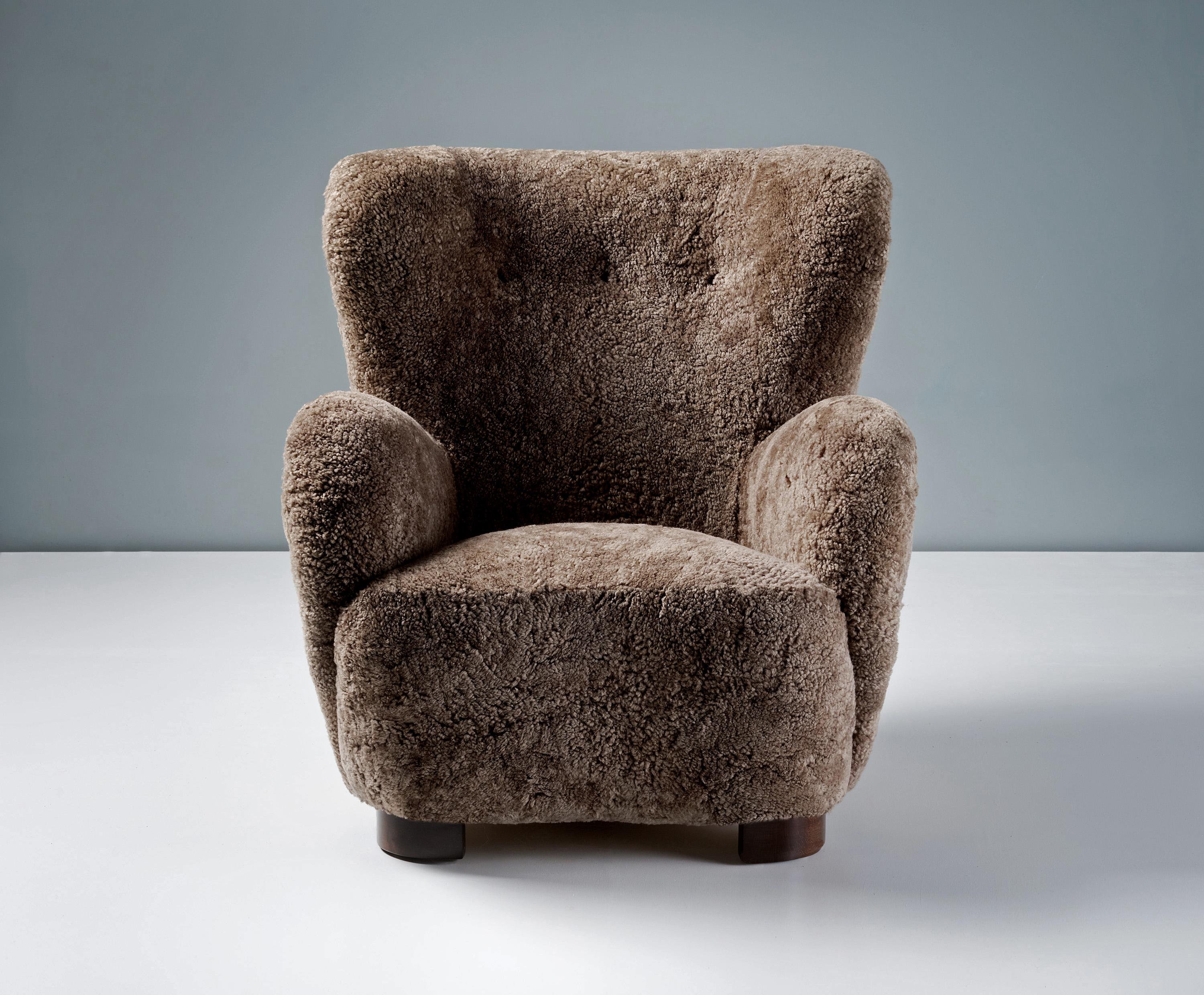 Danish Cabinetmaker Sheepskin Armchair, circa 1940s.

This large lounge chair produced by a Danish Cabinetmaker in the 1940s is typical of Danish lounge chair designs of the day. It features large, curved arms and low, wide, refinished stained beech
