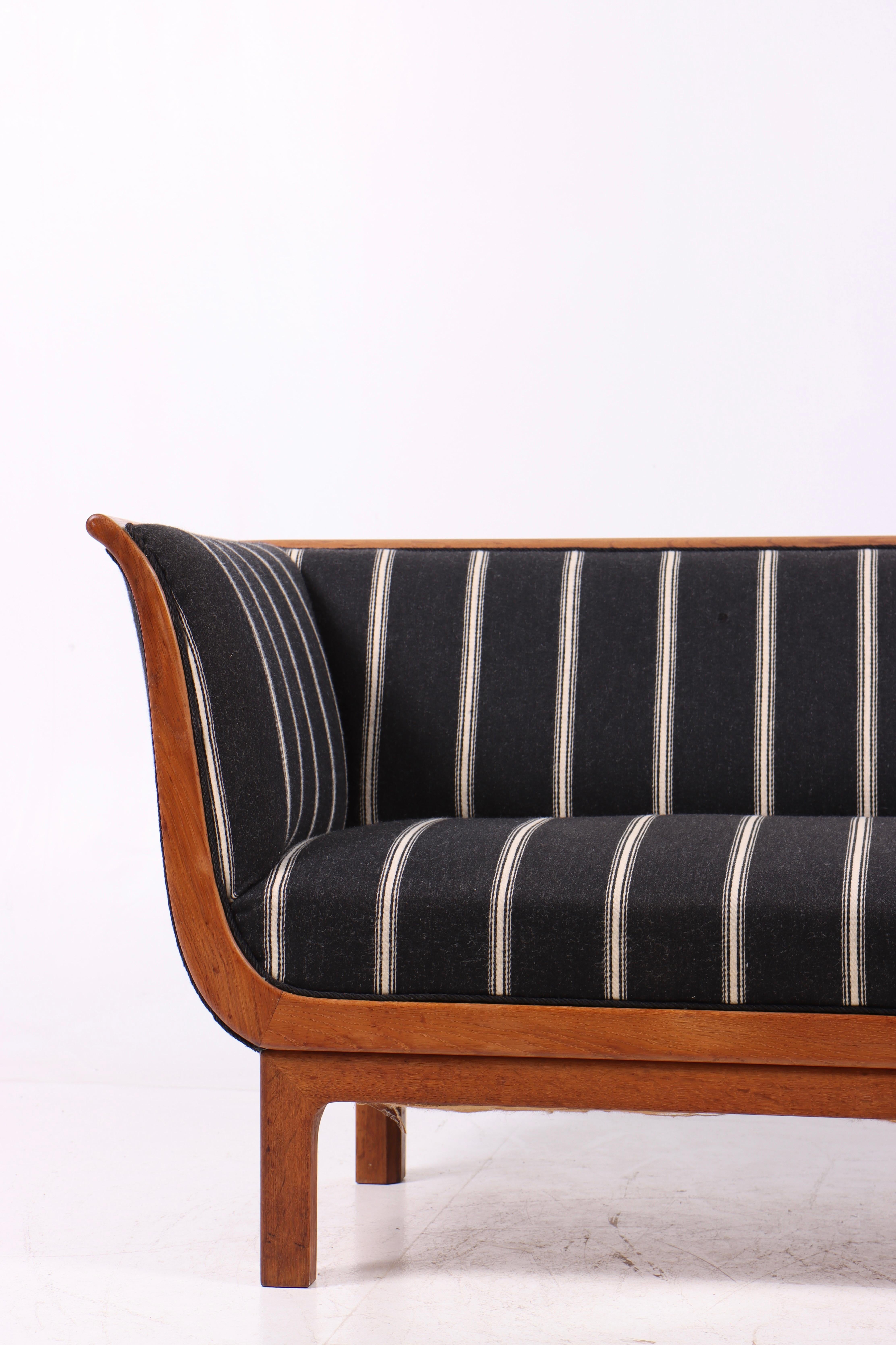 Elegant cabinetmaker sofa crafted in solid oak and upholstered in wool fabric with classic stripes. Produced in Denmark during the 1950s, the piece reflects the high level of craftsmanship and refined quality characteristic of the period.
The oak
