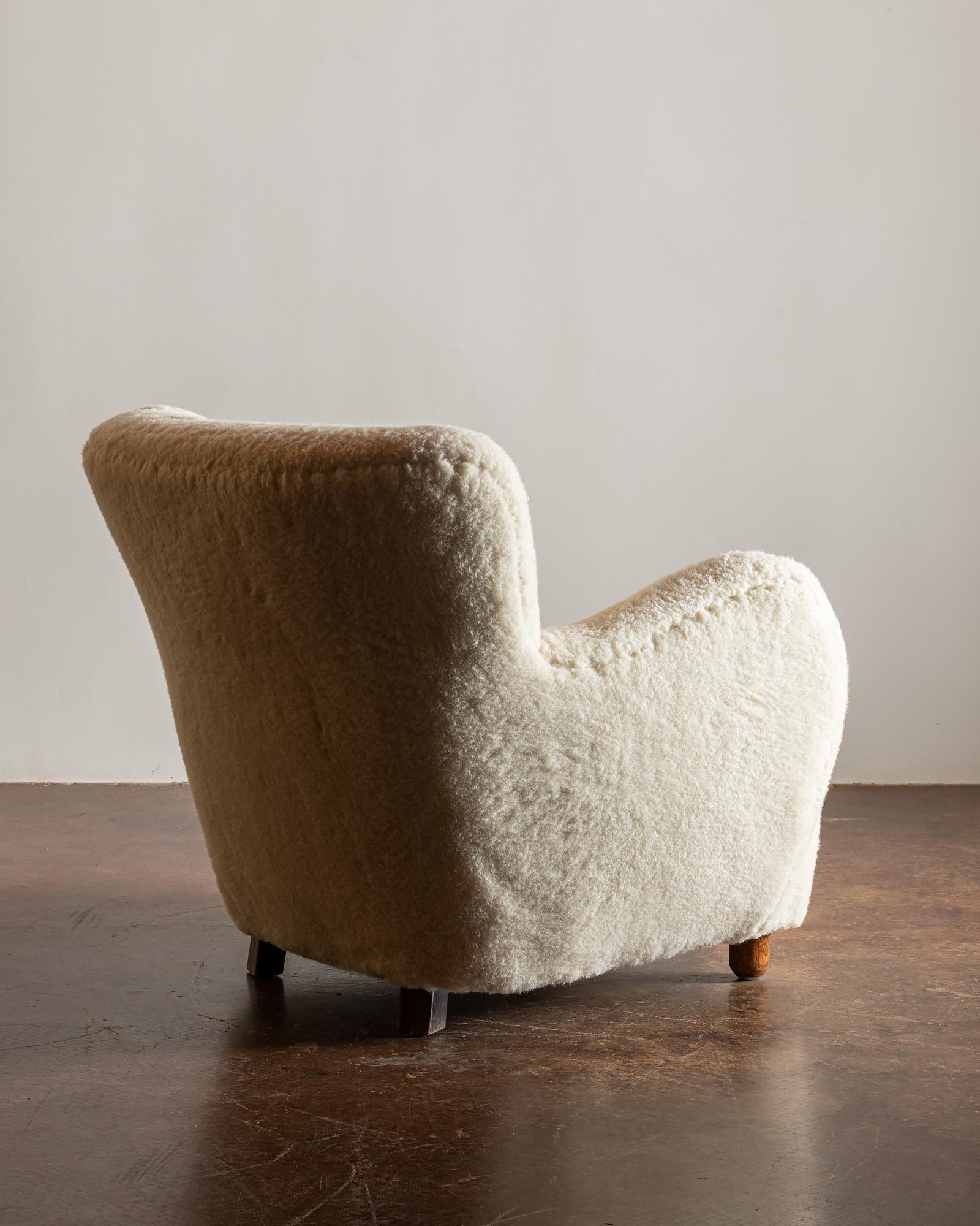 A Classic form--the Danish cabinetmaker's easy chair. This example in light sheepskin with stained beech feet, Denmark, 1940s.