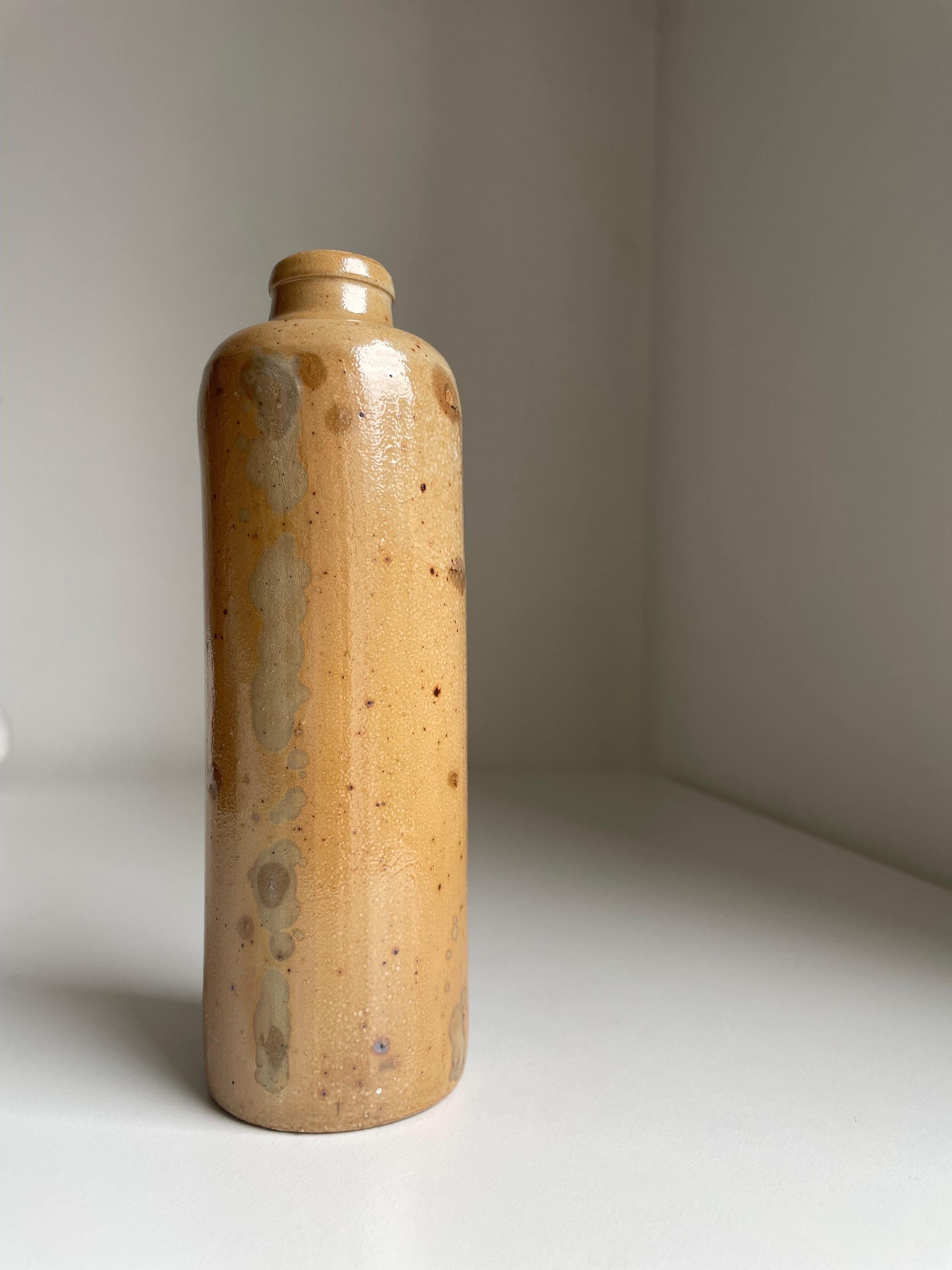 Slim and rustic midcentury ceramic bottle vase with salt glaze in light caramel and brown colors. Beautiful vintage condition. 
Denmark, 1960s.