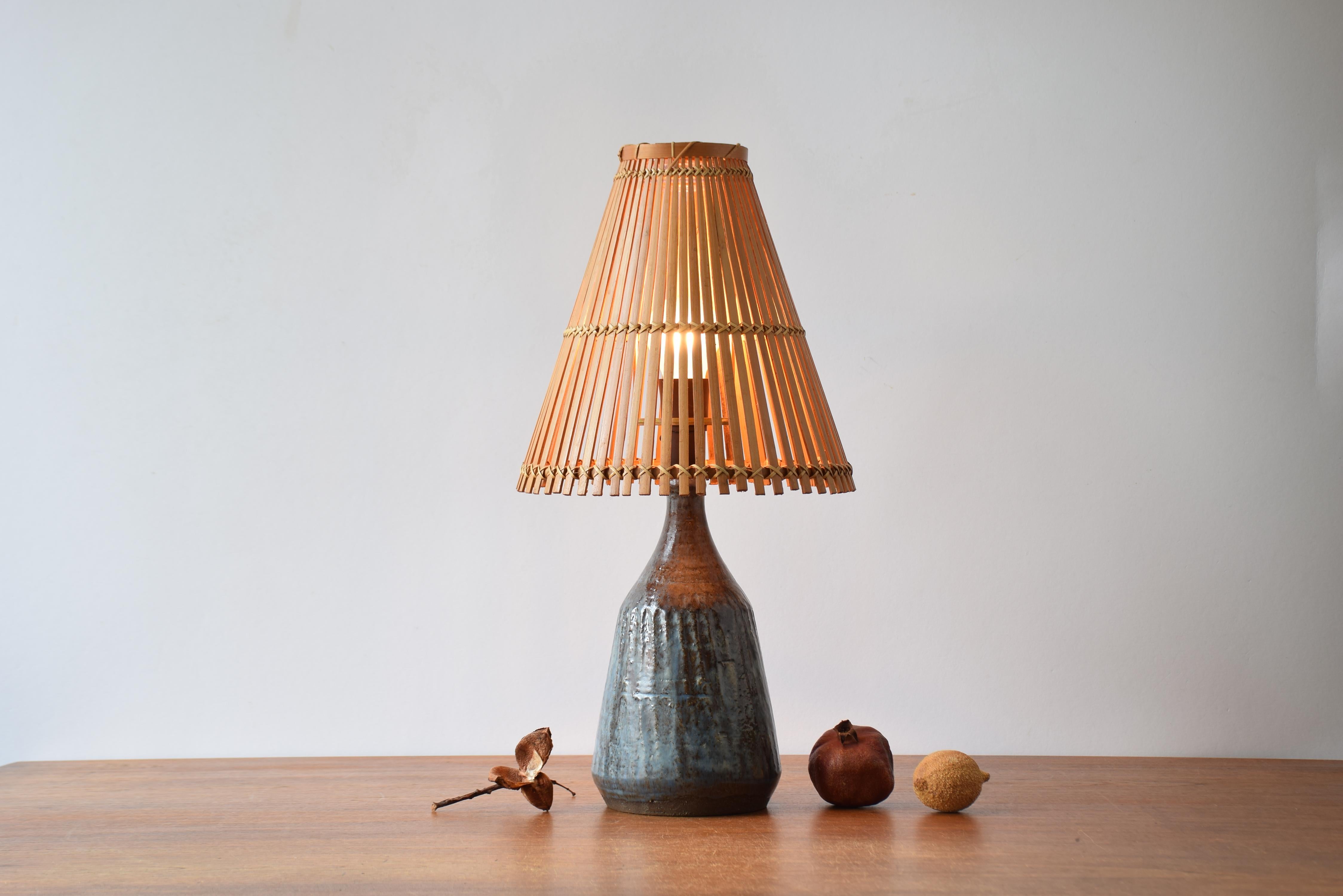 Mid-century ceramic table lamp from a Danish studio workshop. Made ca. 1950s to 1960s. The lamp includes a vintage bamboo lamp shade.

The lamp has a blue and brown glaze.

The lamp isn't signed and the designer is unknown. The style is reminiscent