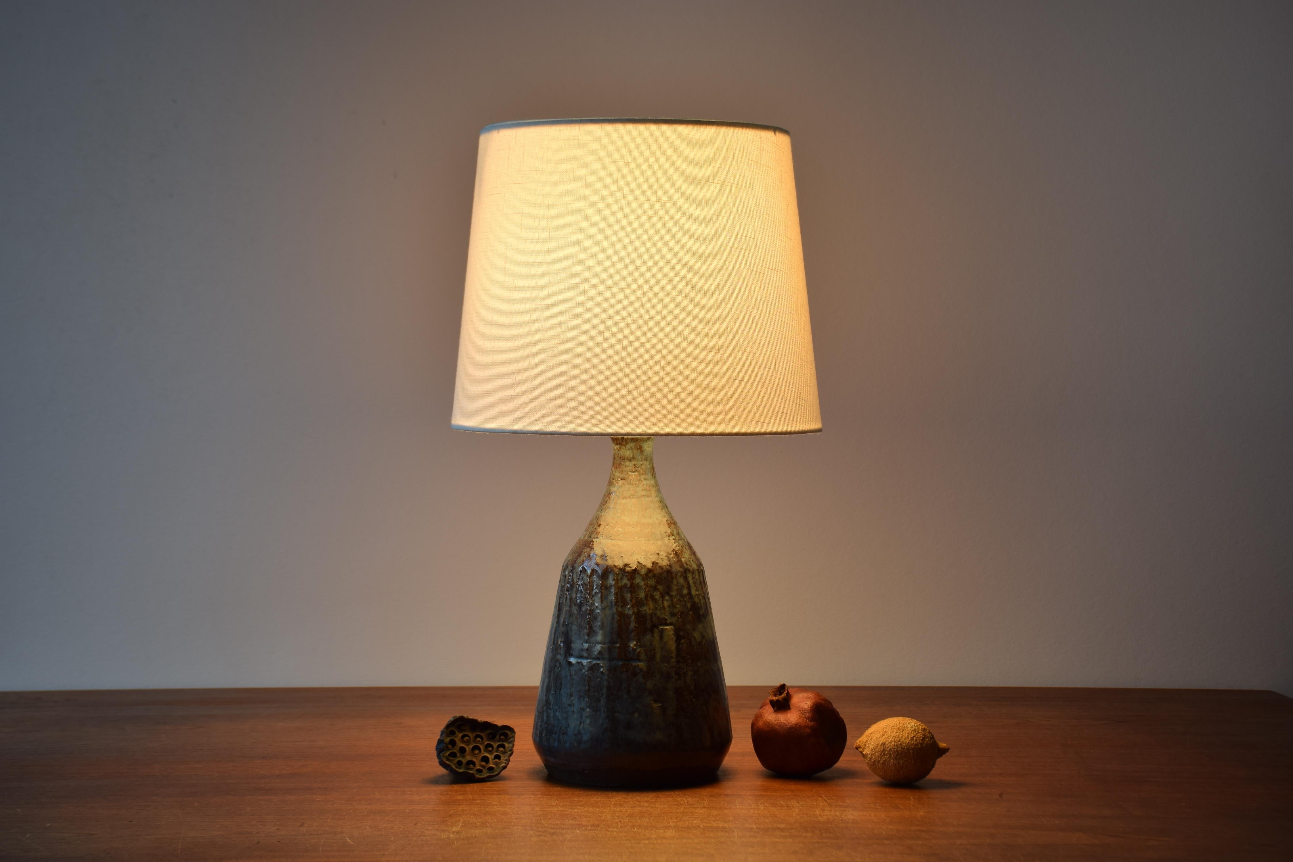Mid-century ceramic table lamp from a Danish studio workshop. Made ca. 1950s to 1960s.

The lamp has a blue and brown glaze.

The lamp isn't signed and the designer is unknown. The style is reminiscent of Gutte Eriksen.

The lamp wears the