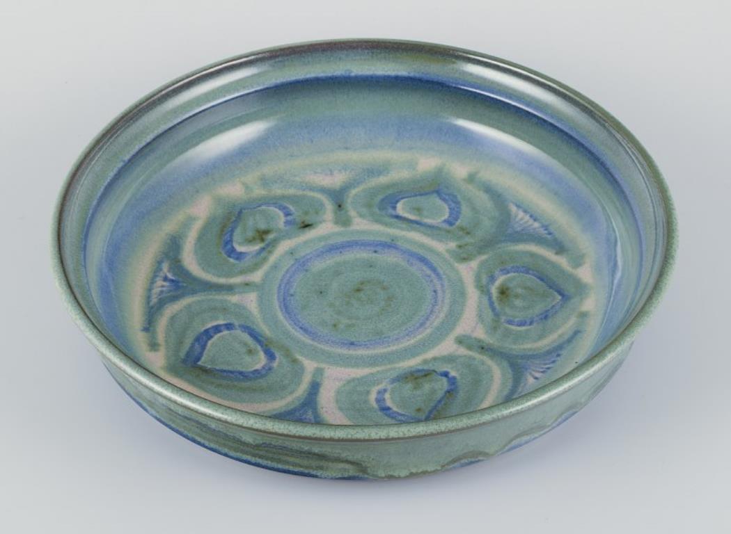 Danish ceramicist.
Large ceramic bowl. Glaze in blue and green tones.
Hand-glazed.
Dating: Ca. 1970s.
Indistinct artist signature and Denmark
In perfect condition.
Dimensions: D 30.0 cm. x H 6.0 cm.