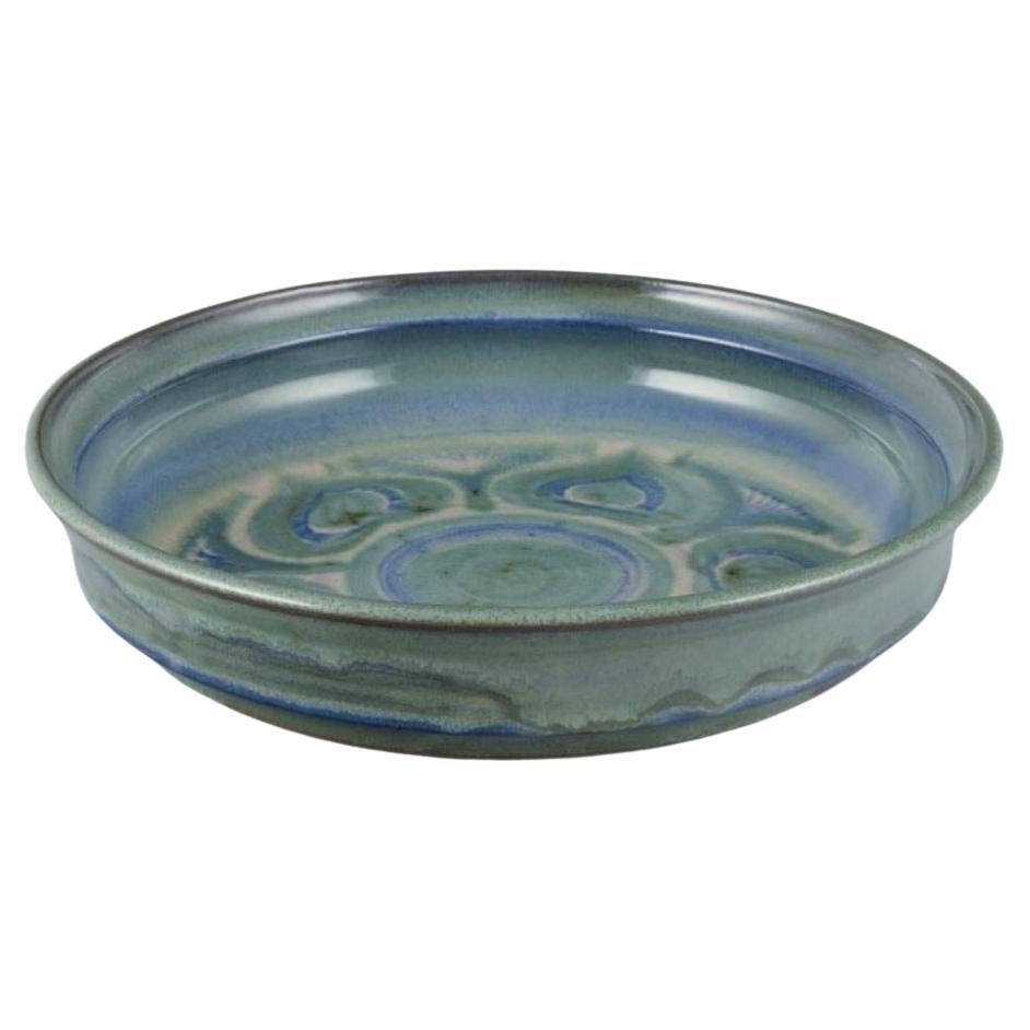 Danish ceramicist. Large ceramic bowl. Glaze in blue and green tones.