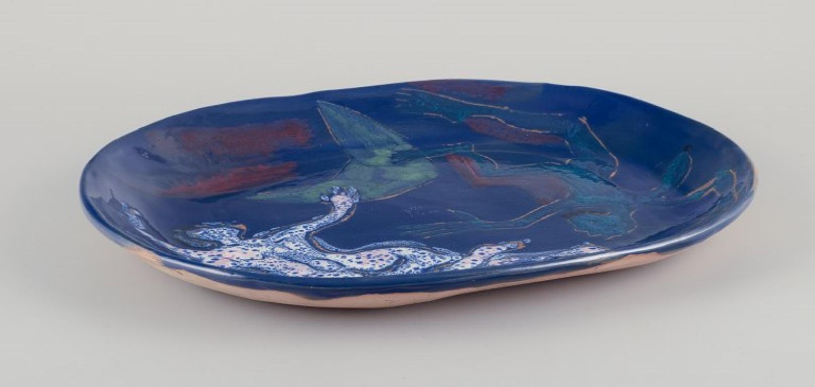 Danish ceramicist. Unique ceramic dish.
Motif of a floating couple. Hand -glazed. Polychrome glaze.
Abstract style.
Ca. 1960s.
Signed 