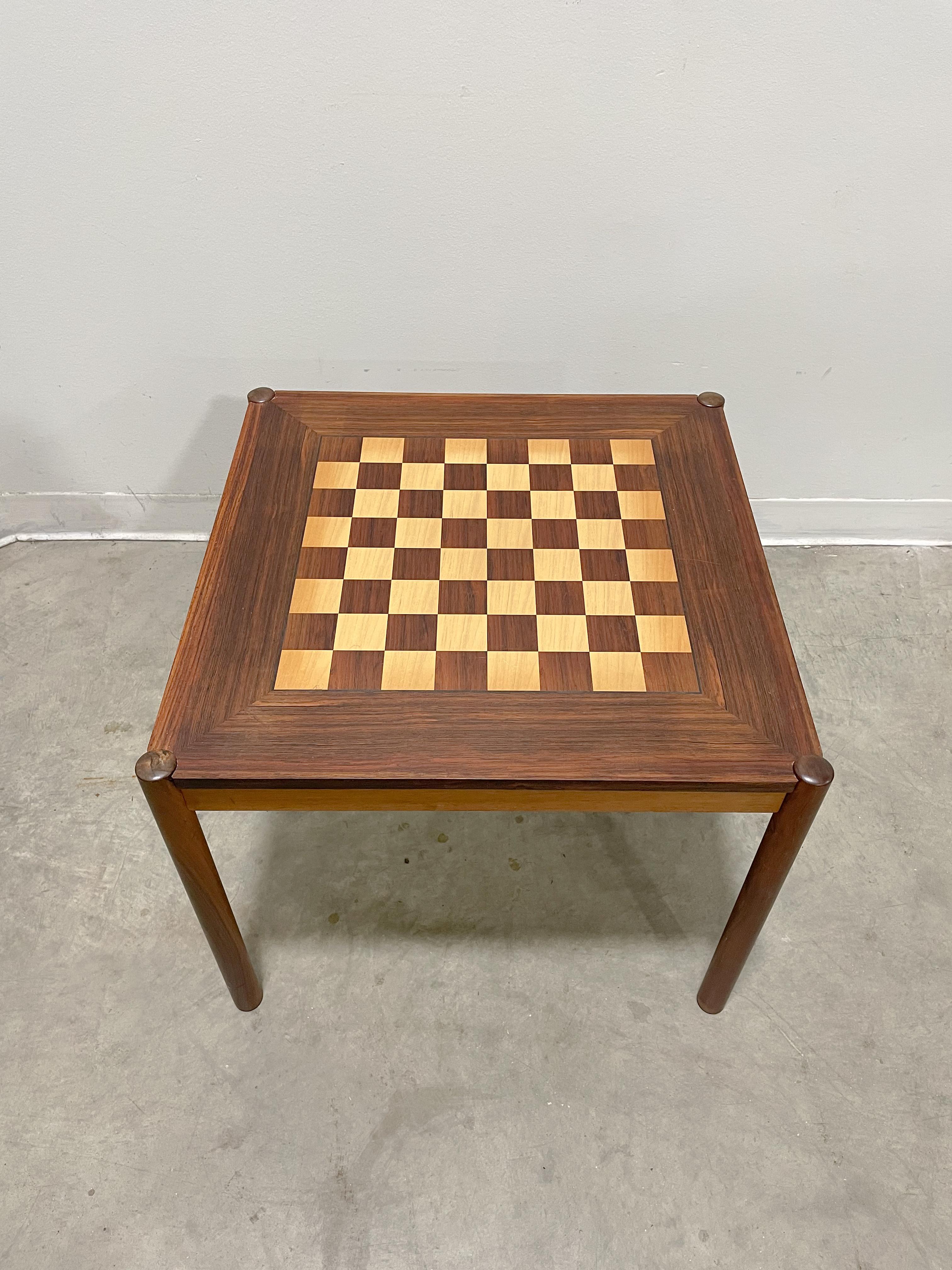 Flip top chess table with storage tray underneath. This table was designed by Georg Petersen. Solid rosewood legs with veneered top and sides. Chessboard on one side of top and rosewood grain on other. Legs bolt on making it easily collapsible for