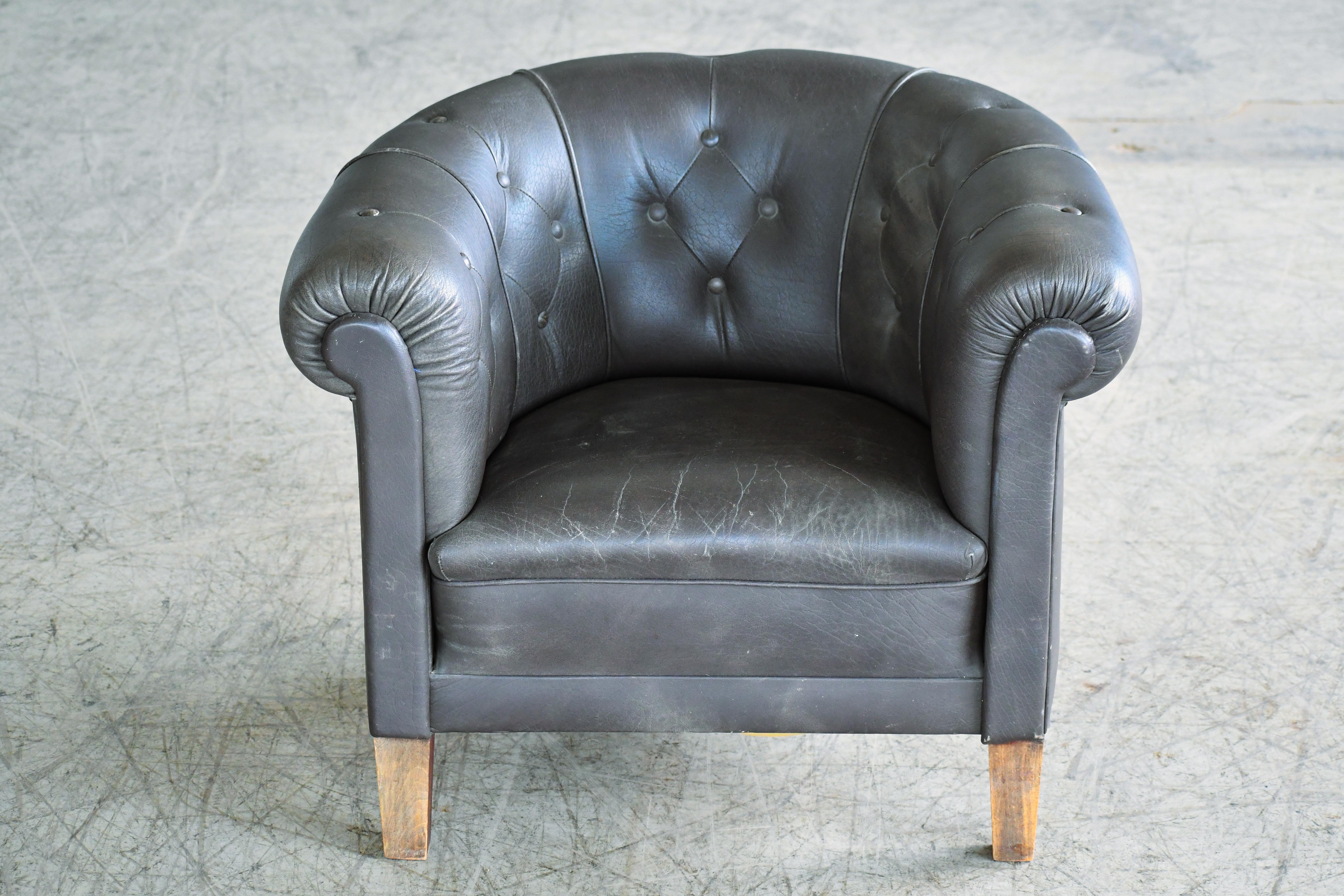 Very nice chesterfield style tub chair made in Denmark around the early 1950's in beechwood and a a charcoal/black leather that remains supple. No rips or tears. Leather decorated with brass tacks. Solid and sturdy with coil springs in both seat and