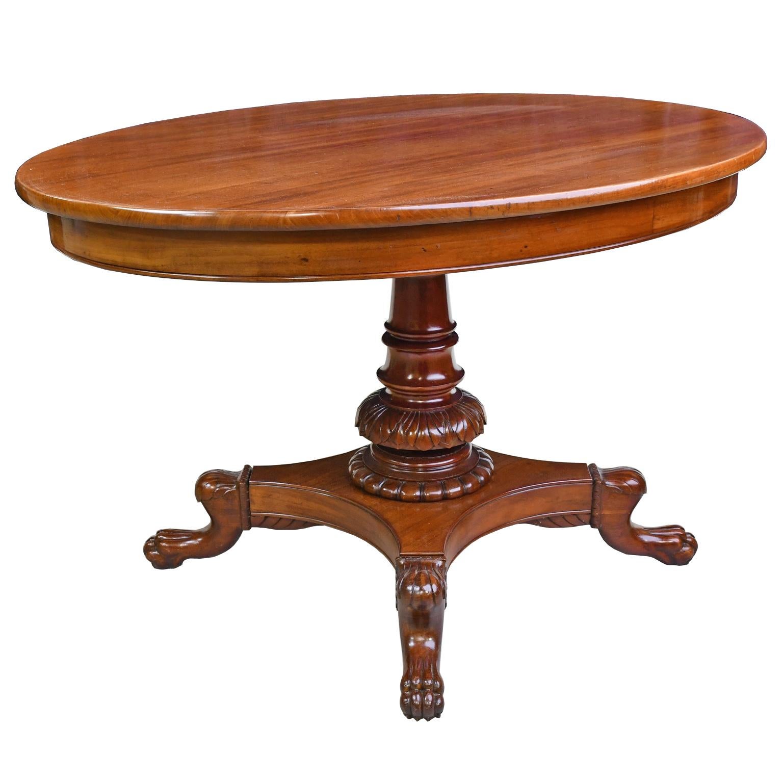 A handsome Christian VIII neoclassical-style tea or breakfast table in mahogany with oval top on foliate-carved baluster-turned column resting on quatre-form pedestal base with carved lion's paw feet. Denmark, circa 1835. Restored in our atelier