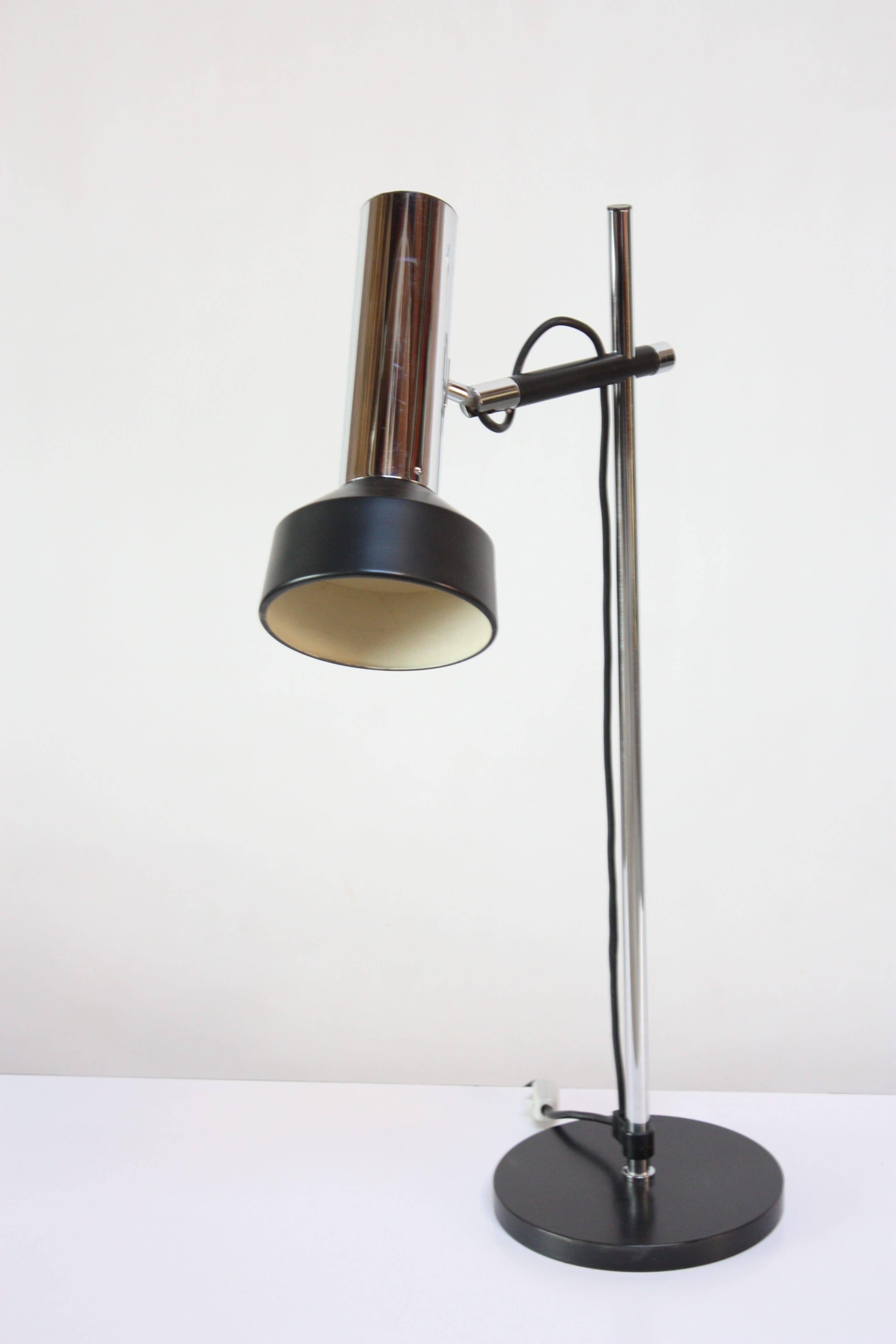 Beautifully designed, yet practical Danish table / task lamp composed of a chromed-metal stem / partial shade and a circular, black painted metal base and shade. Features a black metal clasp at the bottom to hold the cord in place along with a black