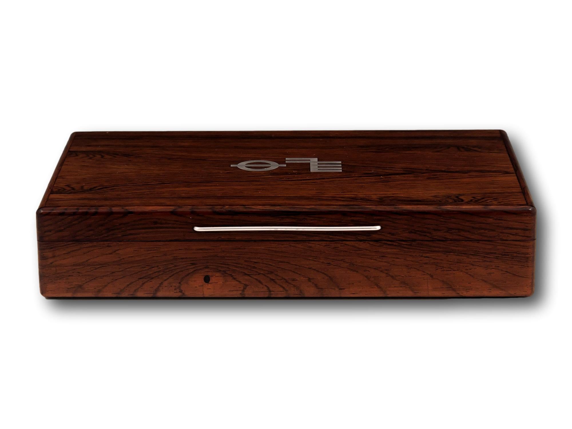 Intarsien mit Plimsoll Line Symbol 

Aus unserer Boxen-Kollektion bieten wir Ihnen diese moderne Zigarrenkiste aus Rosenholz aus der Jahrhundertmitte an. Die Box mit schlanker, rechteckiger Form ist aus massivem Palisanderholz gefertigt und hat eine