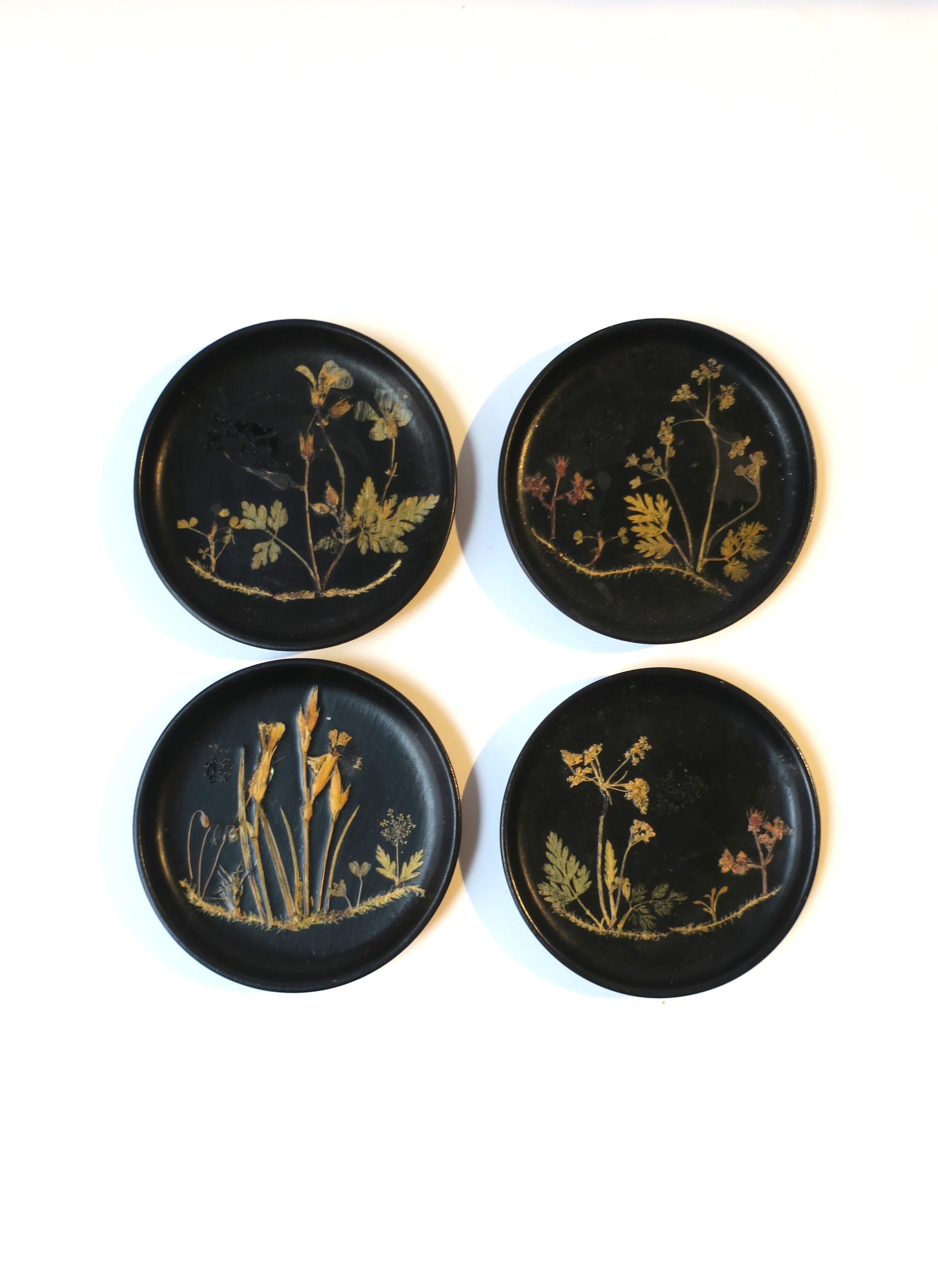 A set of four (4) Danish black wood ebonized cocktail drinks coasters with dried organic botanical design, Midcentury Modern Scandinavian Modern design, circa early to mid-20th century, Denmark. Marked on underside 'Made in Denmark', as shown in