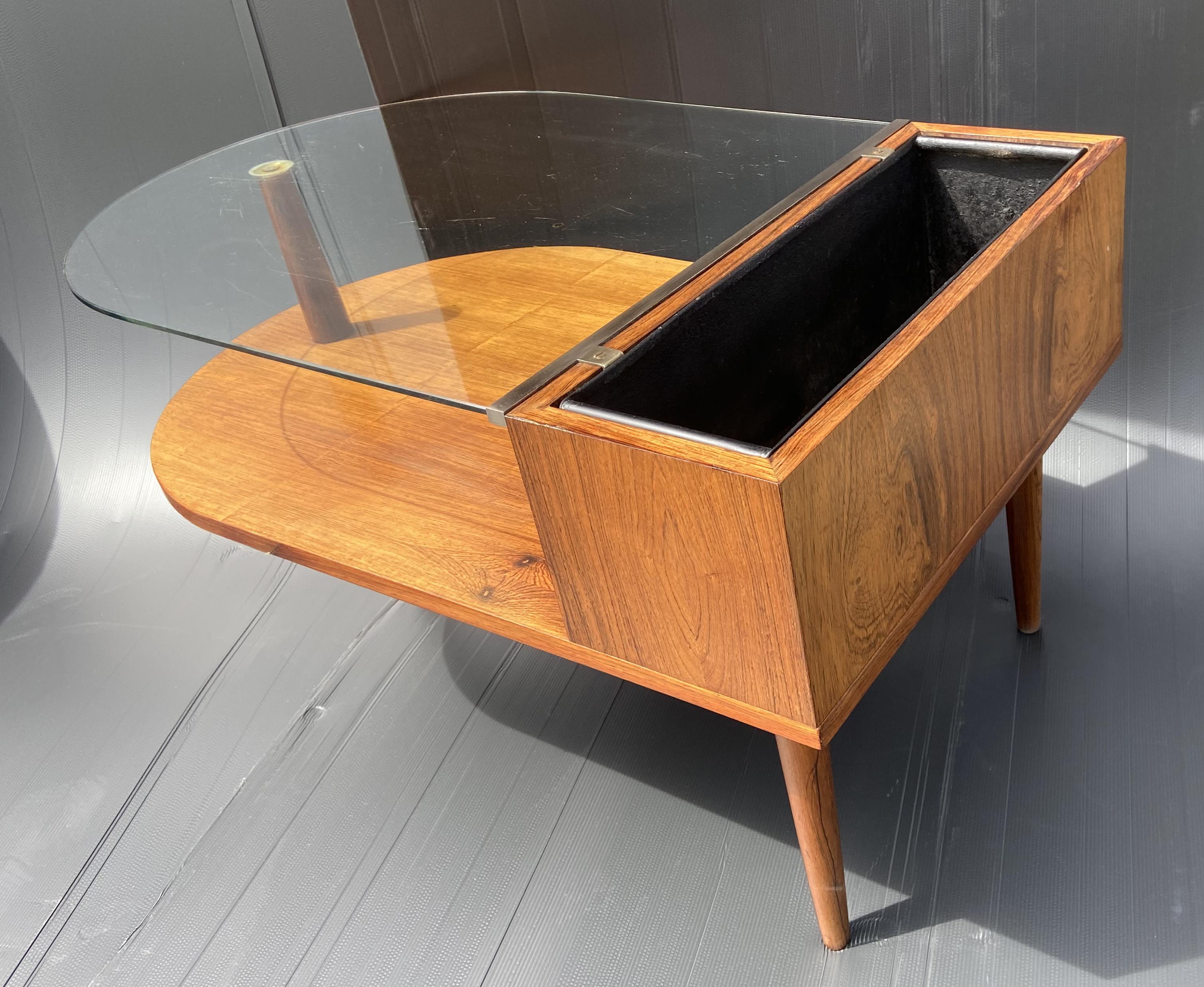 A very nice unusual little piece of Scandinavian Modern furniture, a glass top coffee table with a planter behind and a shelf below, all in very nice original condition.