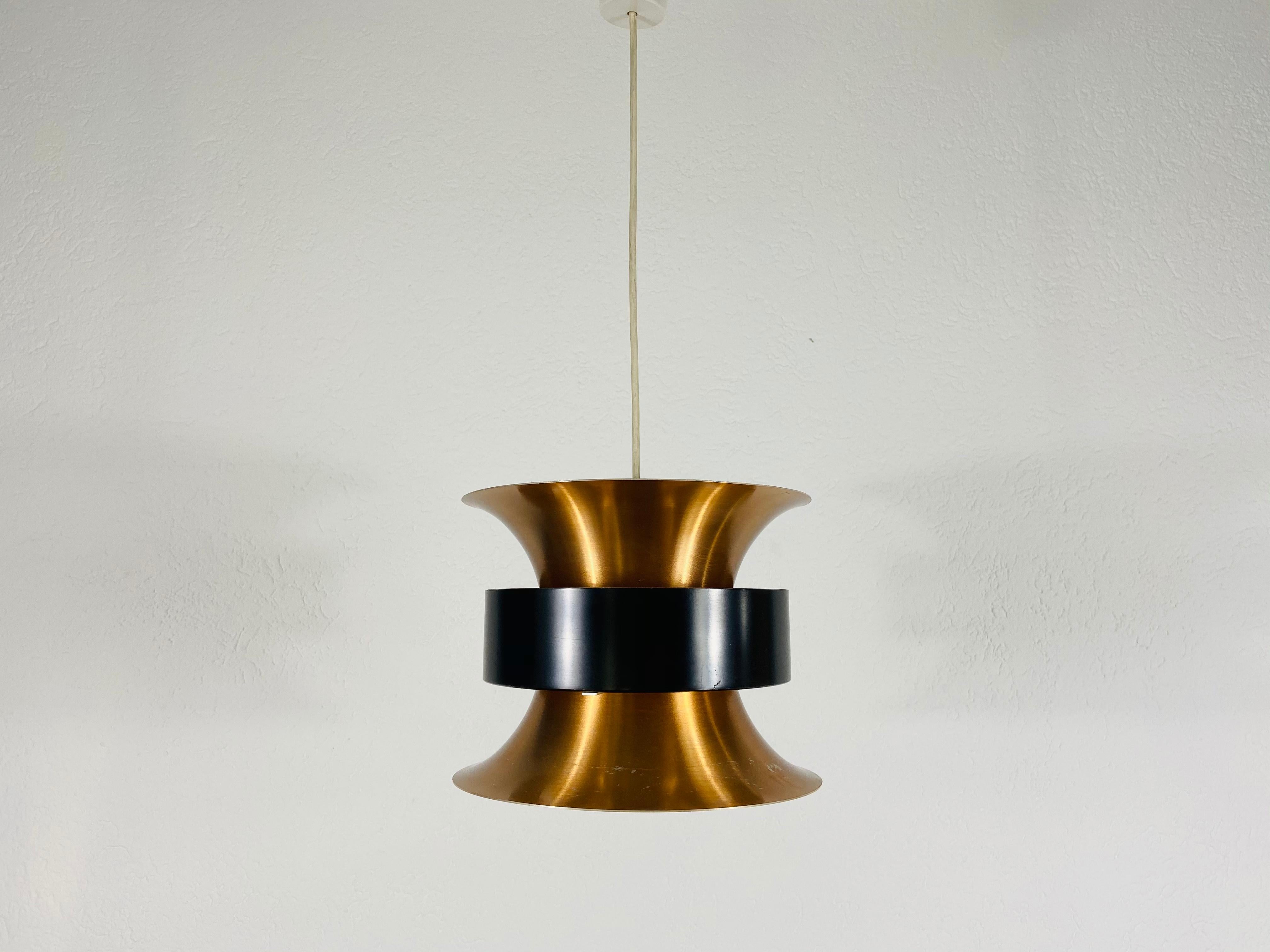 Lampe pendante danoise en noir et cuivre fabriquée en Allemagne dans les années 1960. Le luminaire donne une très belle lumière. Il est fabriqué à partir d'aluminium et de cuivre fins.

Le luminaire nécessite une ampoule E27. Expédition express