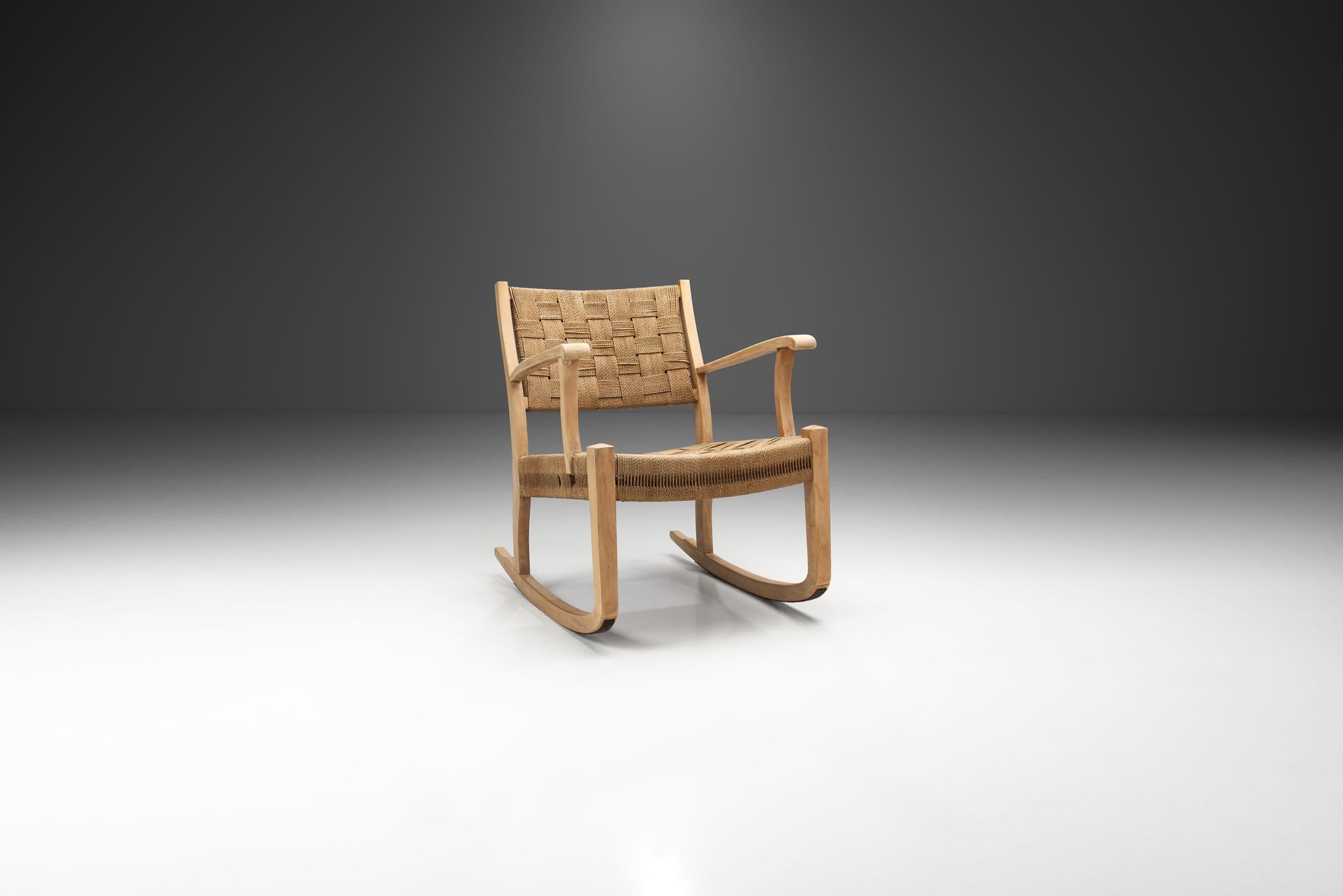 A beech rocking chair, suspended in seat and back with woven paper cord. Twisted paper cord woven across an open wood frame has been used to form the seats of Danish chairs since the 1940s but through the 1950s and 1960s paper cord became perhaps