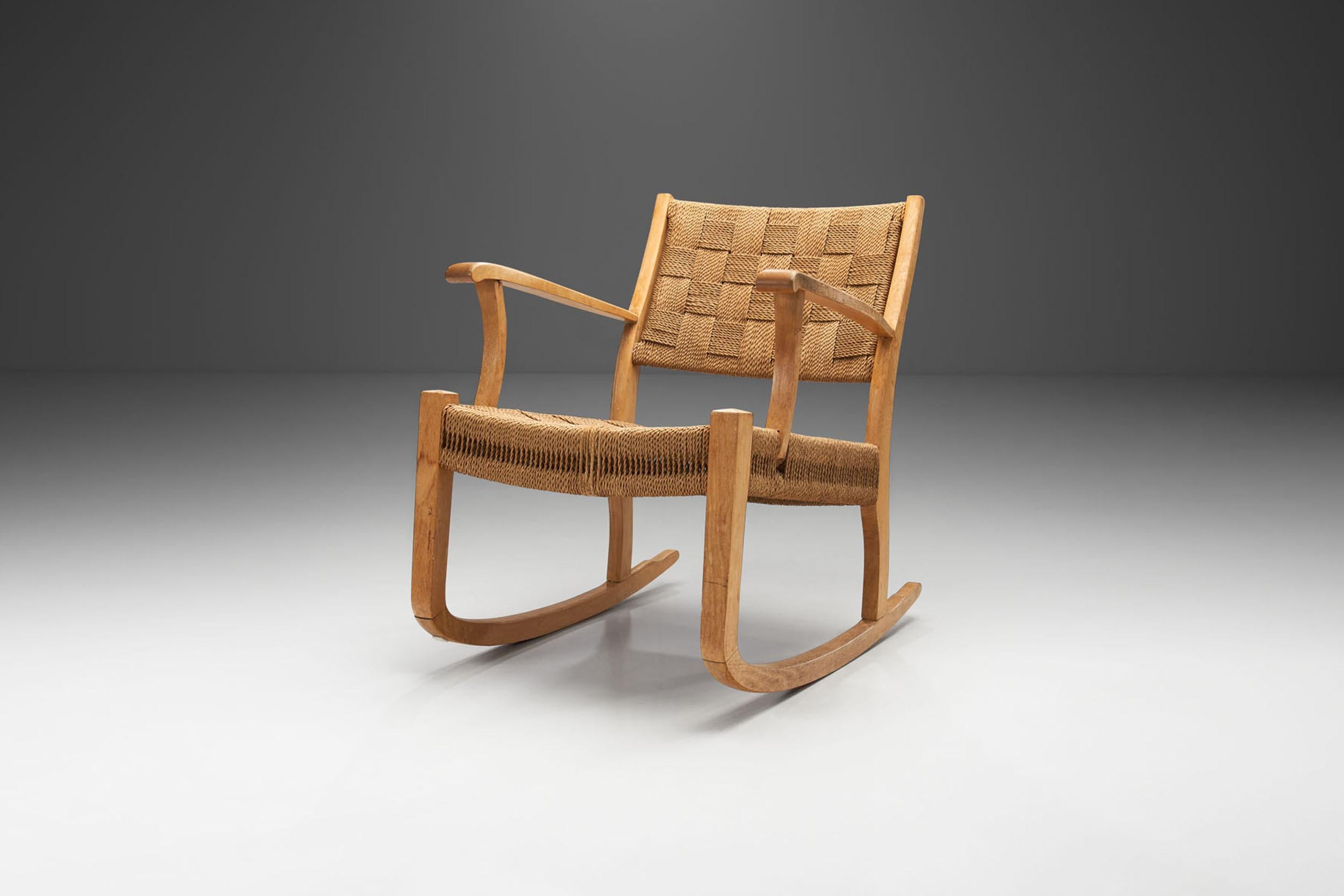 A beech rocking chair, suspended in seat and back with woven paper cord. Twisted paper cord woven across an open wood frame has been used to form the seats of Danish chairs since the 1940s but through the 1950s and 1960s paper cord became perhaps