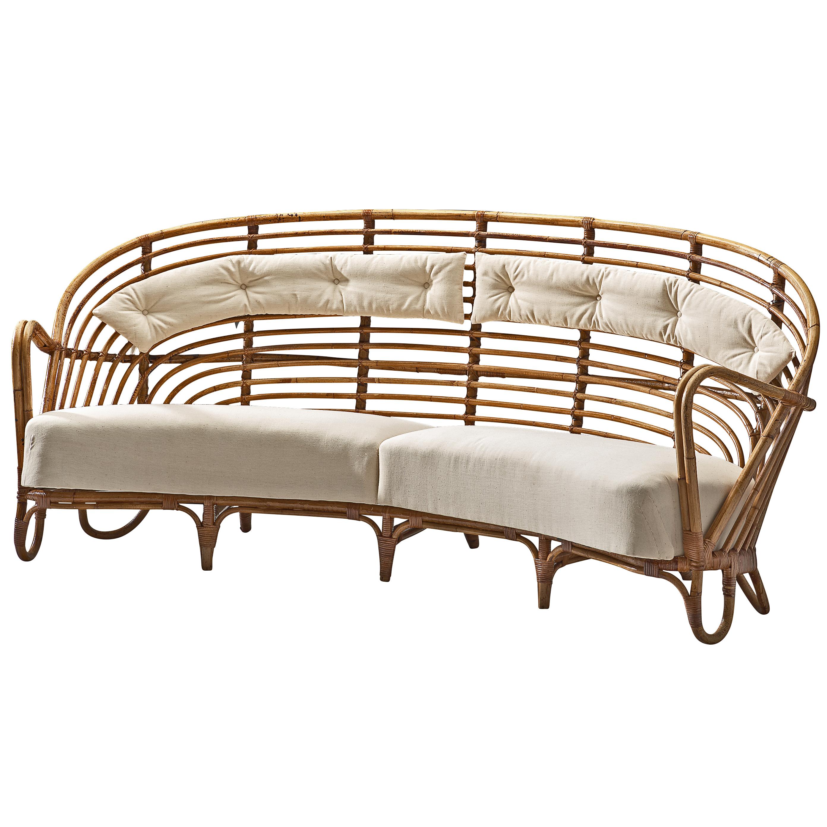 Curved wicker sofa, rattan and fabric, Denmark, 1936.

Stunning wicker sofa featuring rounded and airy structure executed in rattan. The seat is slightly curved and features a thick cushion to comfortably sit on. The backrest is rounded and the