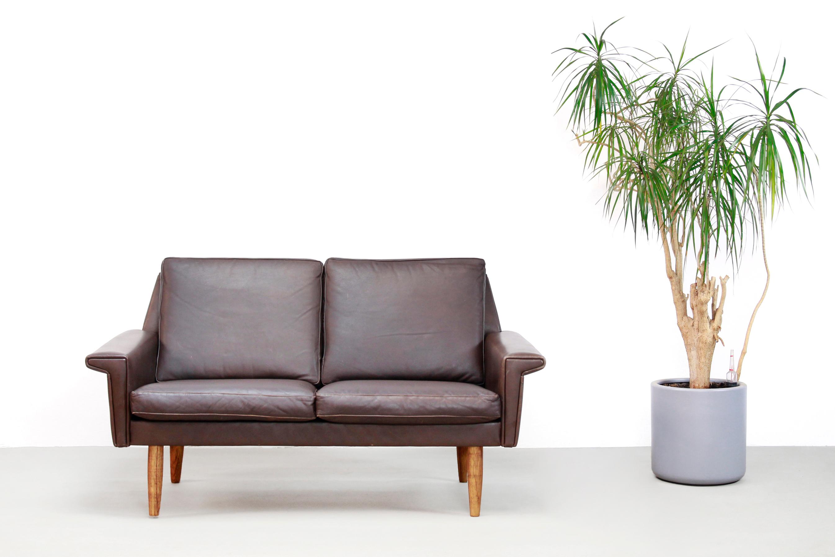 Dark brown leather Danish design sofa, produced by Vejen Polstermøbelfabrik from Denmark. This two-seat is made of brown leather with conical light wooden legs. The sofa has a very beautiful Mid-Century Modernist design which appearance does not