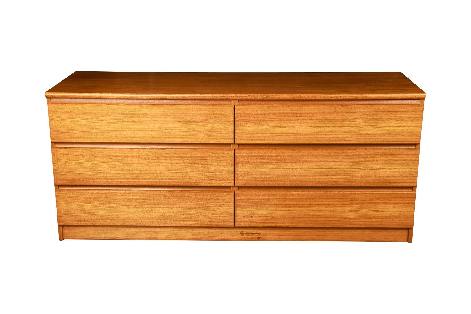 Attractive long low Danish modern sleek smooth face teak 6 long low dresser. This is a very simple yet modern 6 drawer design. Each drawer has beautiful medium tone stunning teak grains with attractive inset slit drawers carved out minimal pulls. At