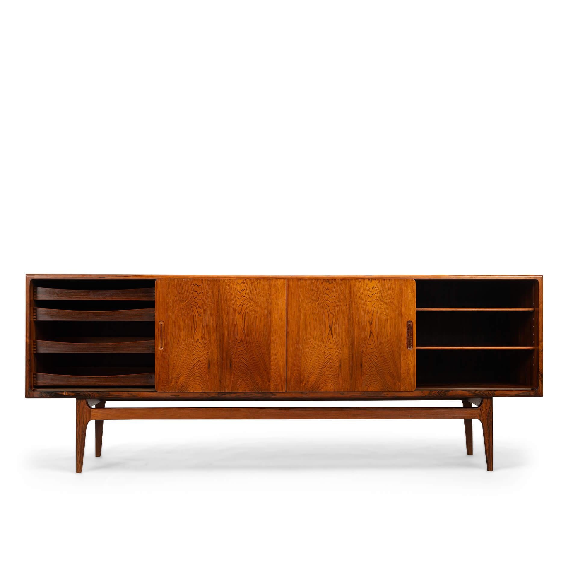 Danish design sleek Mid-Century Modern design! The cabinet has a beautiful subtle drawing of the rosewood or rosewood veneer. It's what we call a low sideboard. The print is the same on all doors. We also see handles that subtly disappear.