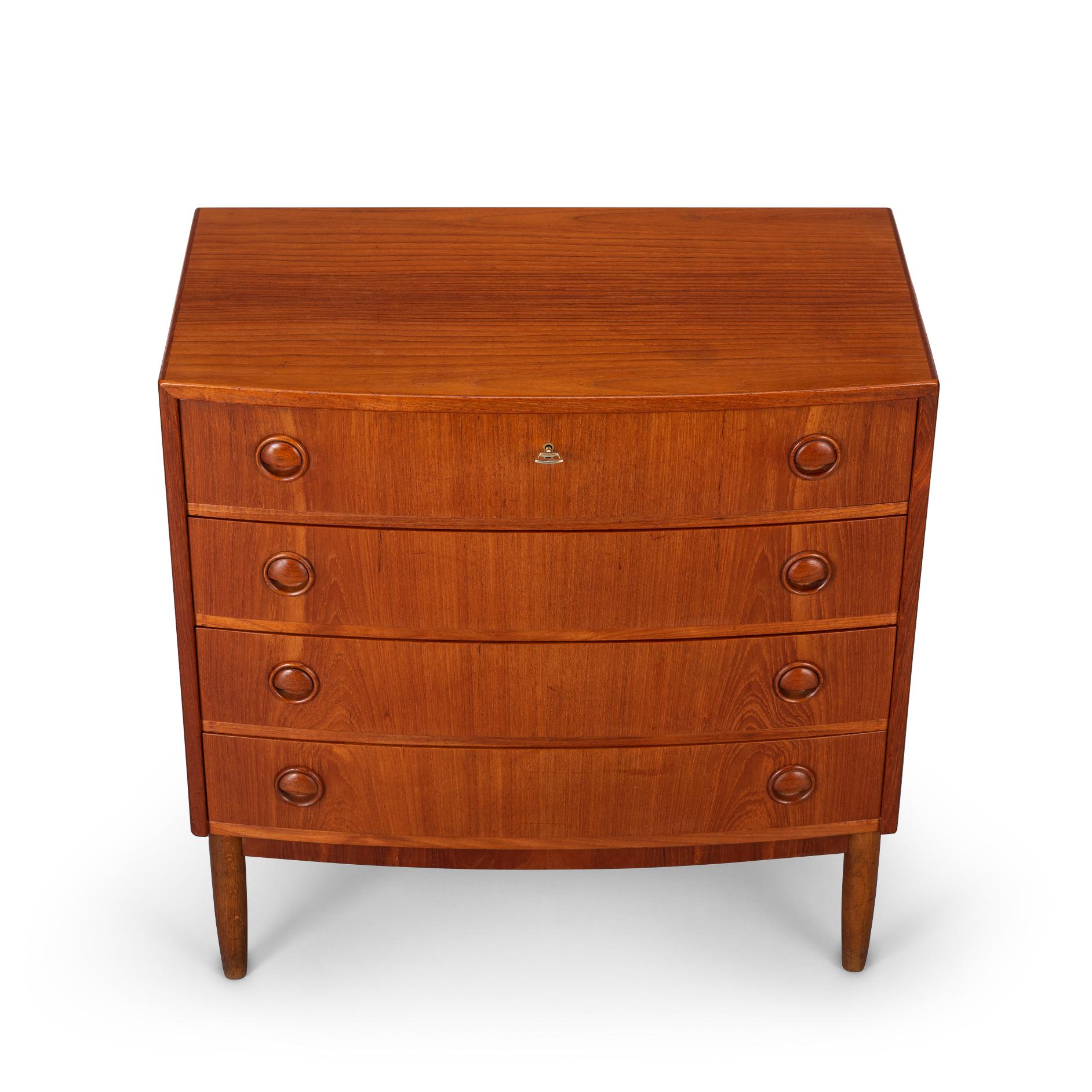 This Danish well fed shaped vintage chest of drawers in teak veneer was made in the early 60s. Four curved drawers with special round handles, so very characteristic of the time, provide the allround sixties look. Top drawer can be locked at your