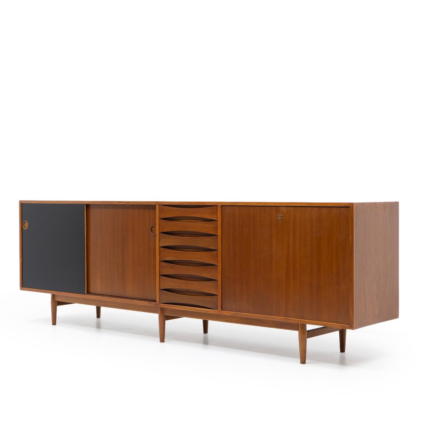 The 1950s Danish-designed Triennale sideboard, created by Arne Vodder (model 29A), is named after its debut at the Milan Triennale. Crafted by the esteemed Danish furniture manufacturer Sibast, this exquisite piece showcases a teak veneer structure.