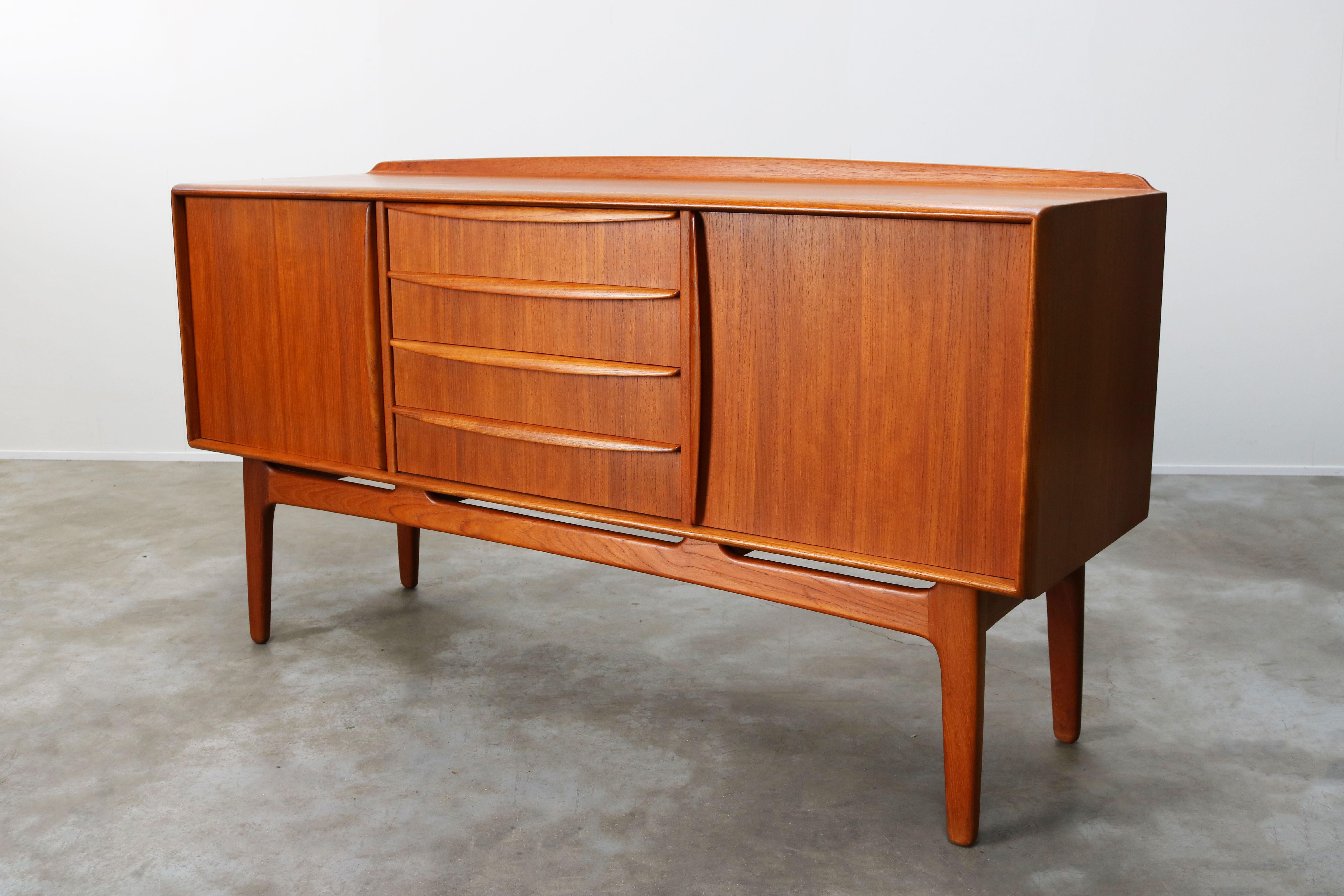 Magnificent Danish design credenza / sideboard in teak designed by Svend Aage Madsen for K. Knudsen & Son in the 1950s. The sideboard has wonderful organic lines in a warm teak wood with stunning wood grain. The top of the sideboard has a upstanding