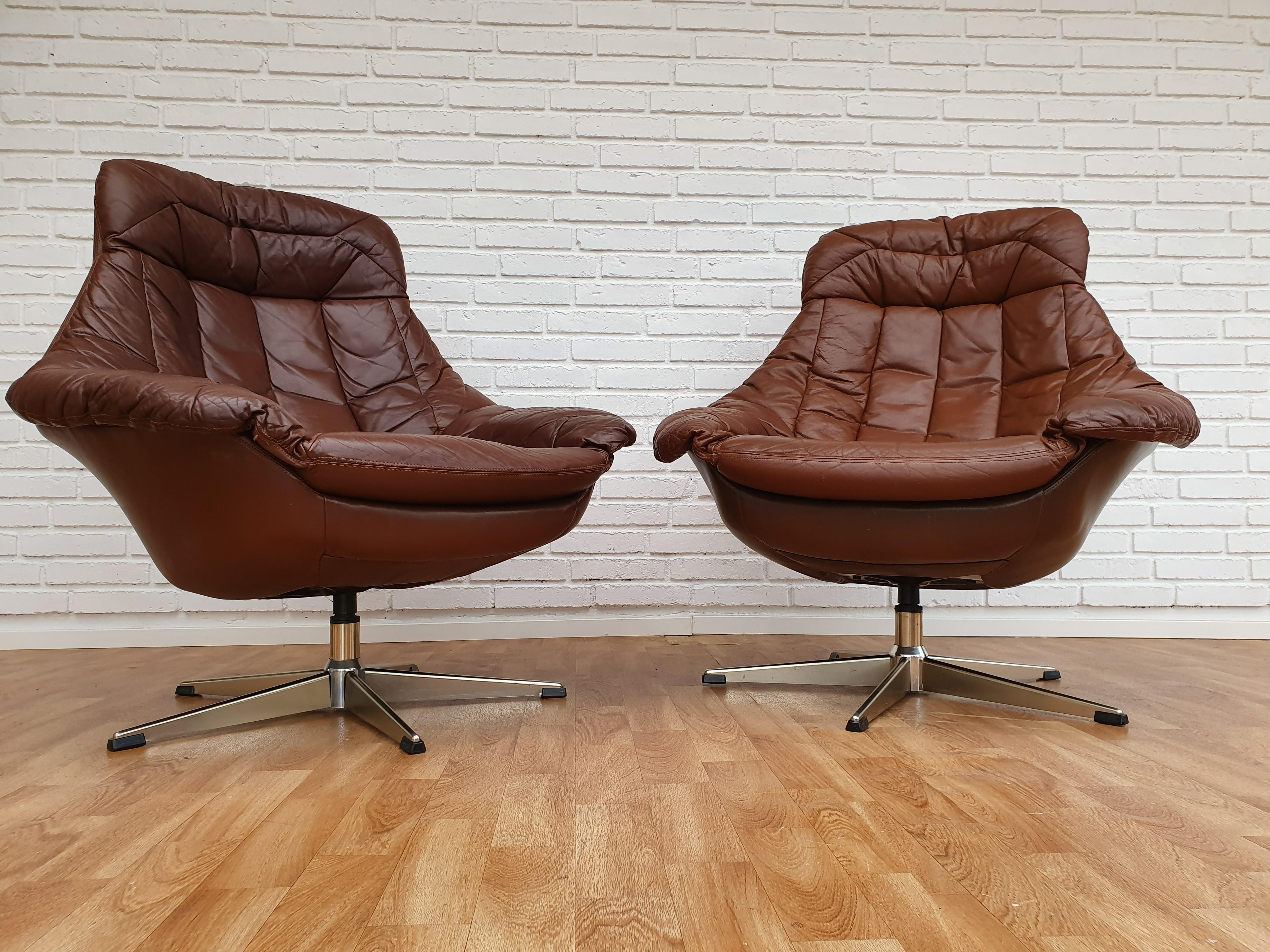 Henry Walter Klein, high-backed armchairs, swivel center column, 1970s. Lounge chairs upholstered in patinated brown leather, profiled swivel center column with five pass metal feet. The chair is used co-cleaned and renewed leather. Very good