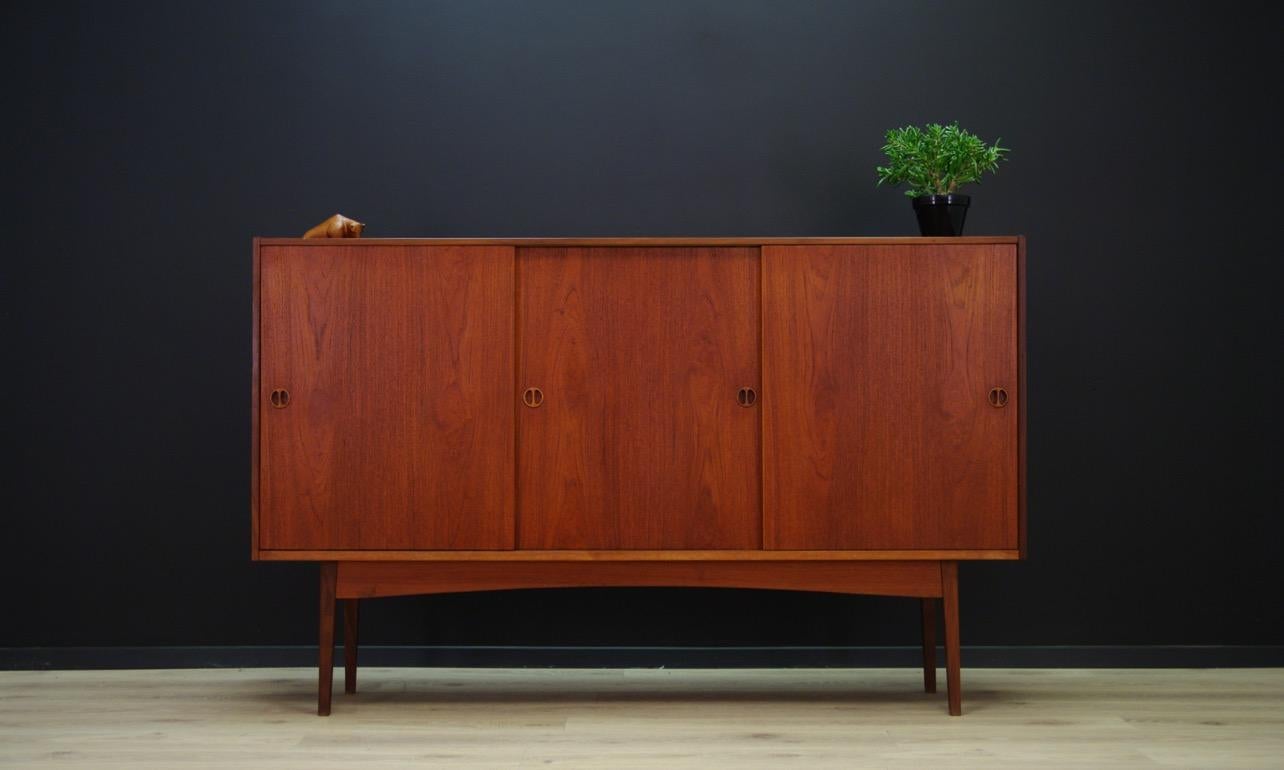 A unique Scandinavian high board from 1960-1970, Danish design. The furniture has a spacious interior with shelves behind the sliding door. The whole is veneered with teak, legs made of solid teak. Preserved in good condition (small dings and