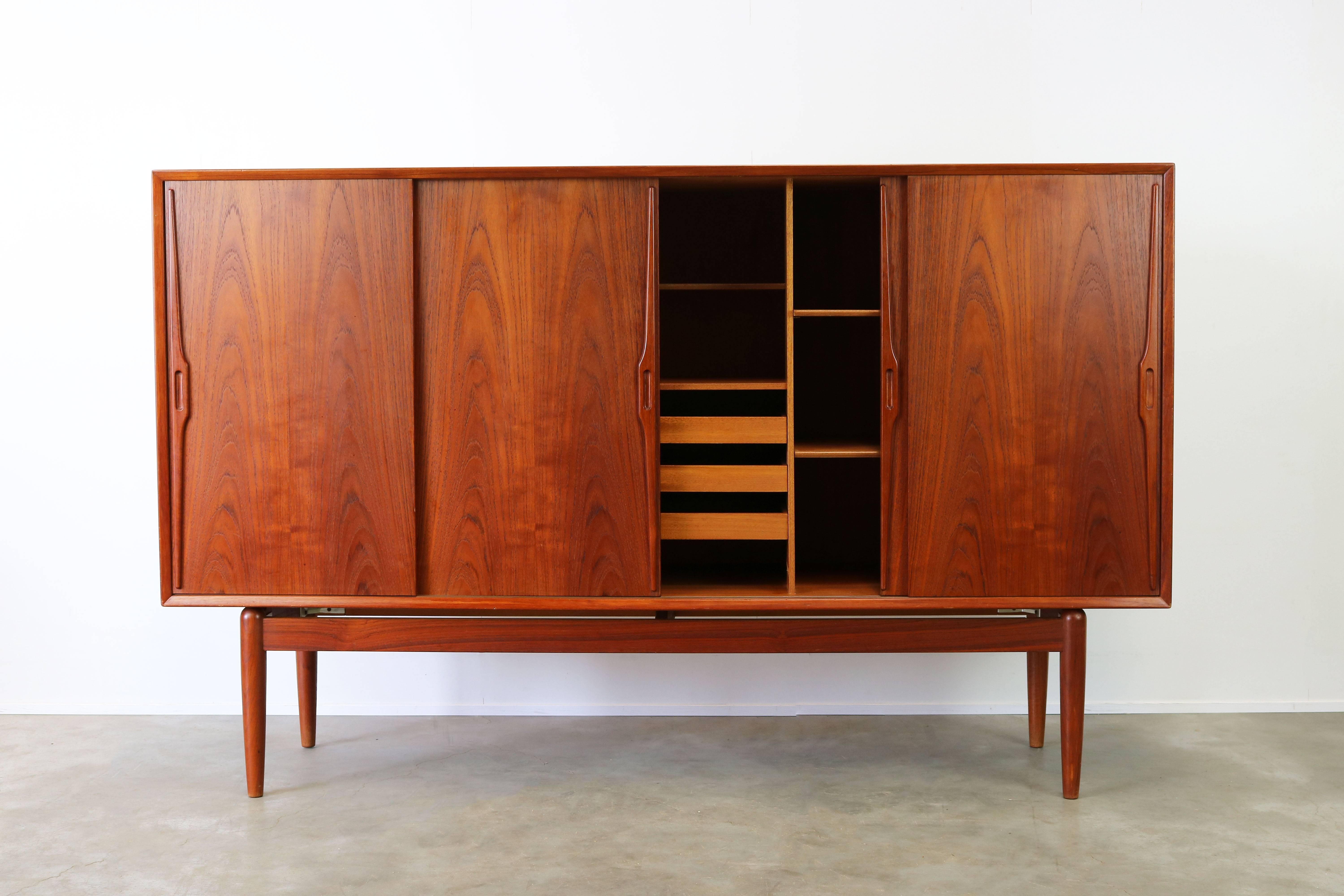 Unique Danish design highboard or cabinet by Gunni Omann in sculpted teak 1950. Wonderful sculpted organic teak with stunning woodgrain. This highboard has a rare base that makes the upper part of the cabinet appear to float. The interior has