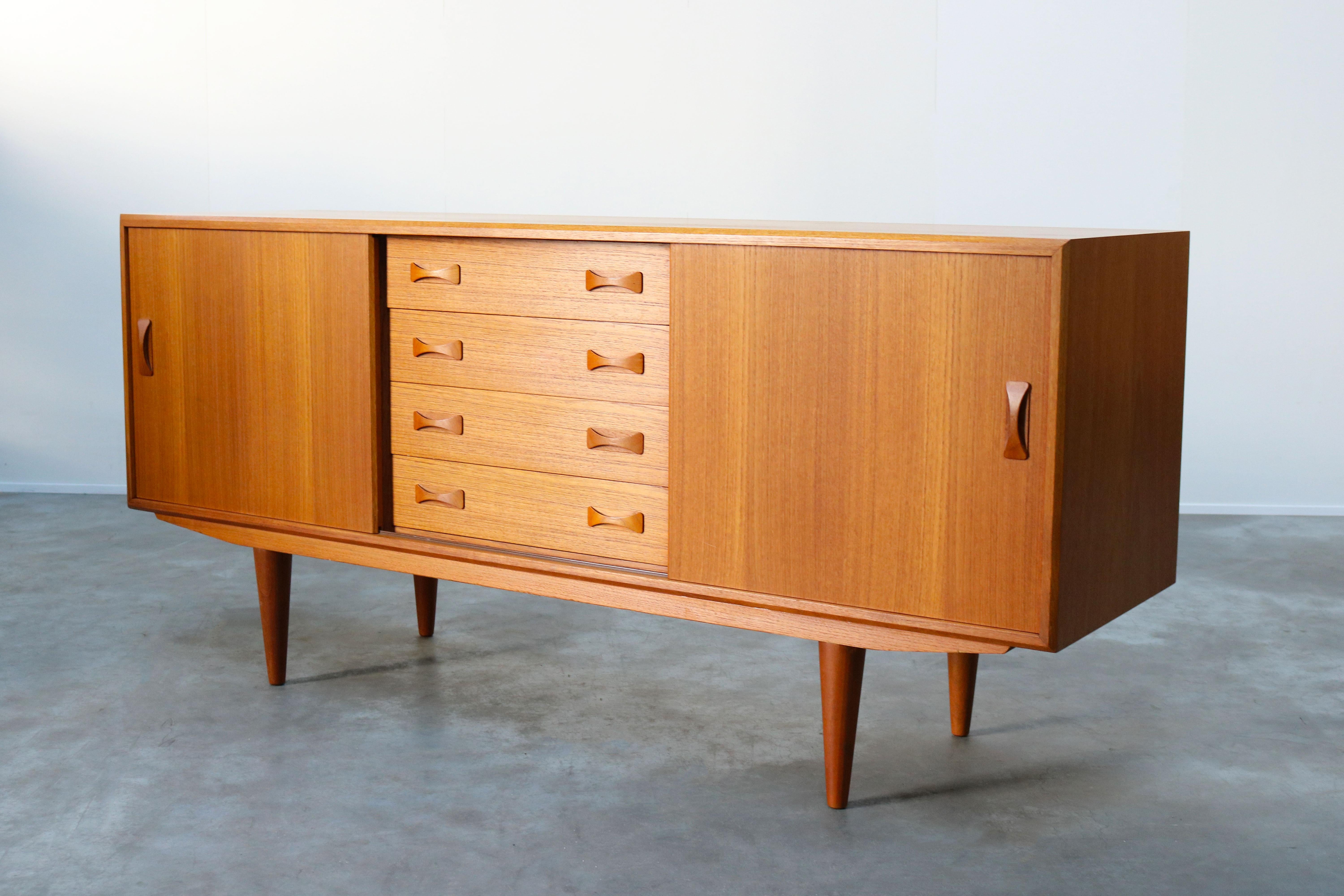 Danish teak sideboard/credenza designed by Clausen & son in the 1960s. Wonderful sculpted handgrips and clean design. The sideboard has four drawers, sliding doors and plenty of storage space. A wonderful example of Danish modern design. Sideboard