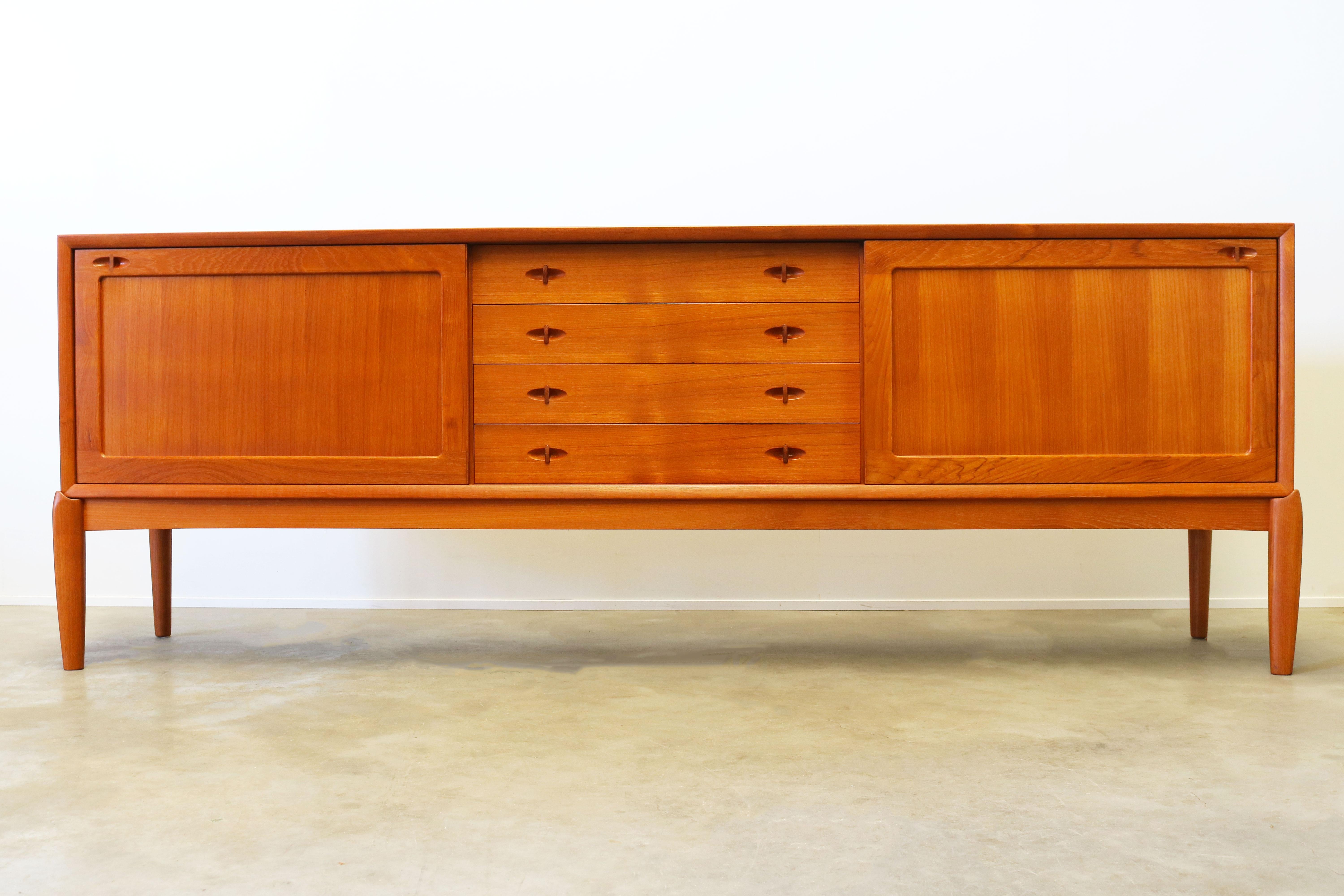 Magnificent Danish design sideboard designed by H.W. Klein for Bramin in the 1950s. The sideboard is made from solid teak wood and is famous for its combination between straight and organic lines with in particular the organic (solid wood) sculpted