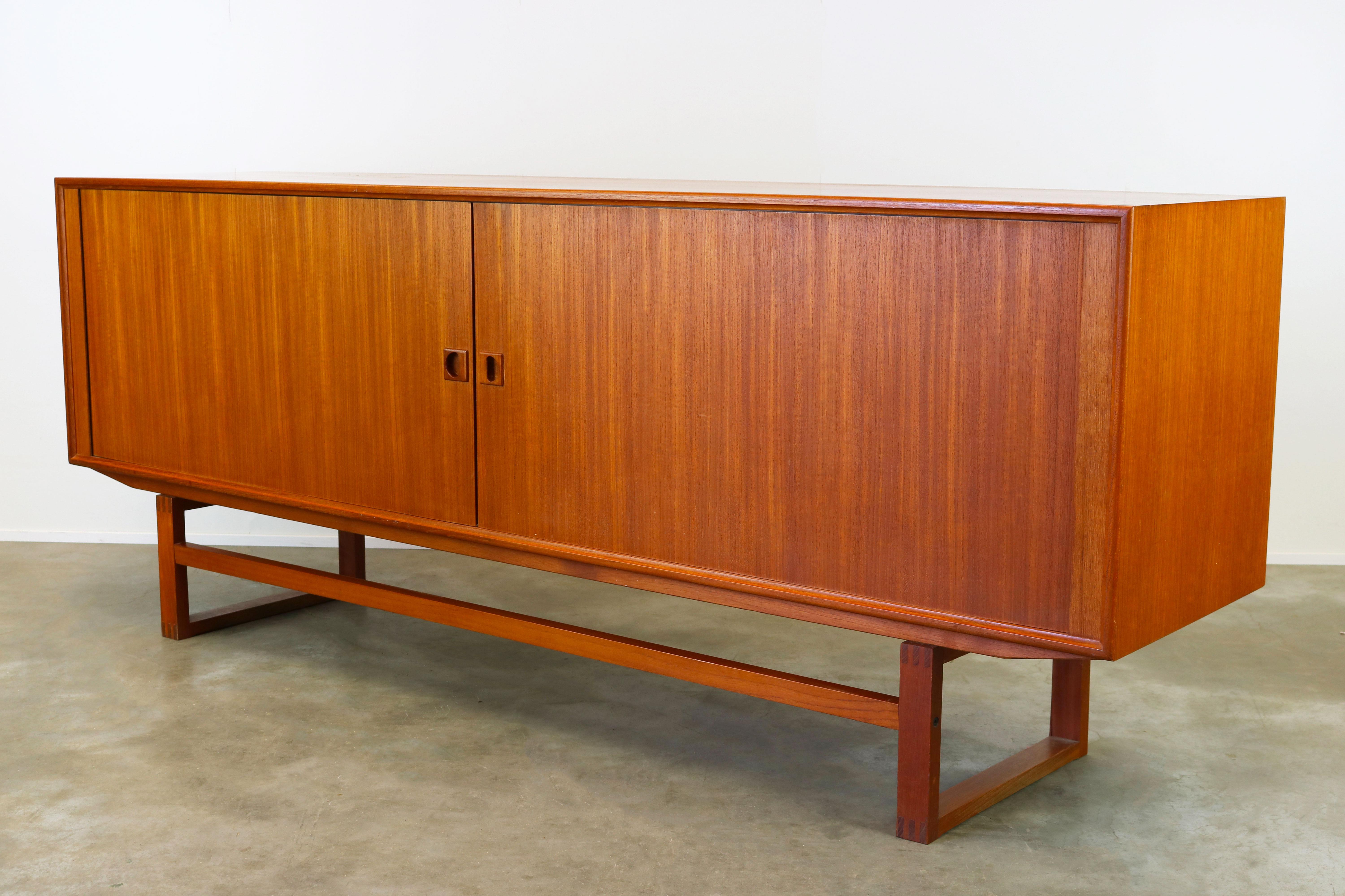 Wonderful Danish design sideboard designed by Axel Christenen for Aco Mobler in the 1950s. The sideboard is made from teak and has beautiful tambour doors who disappear completely when opened. Characteristic for this sideboard is the square base