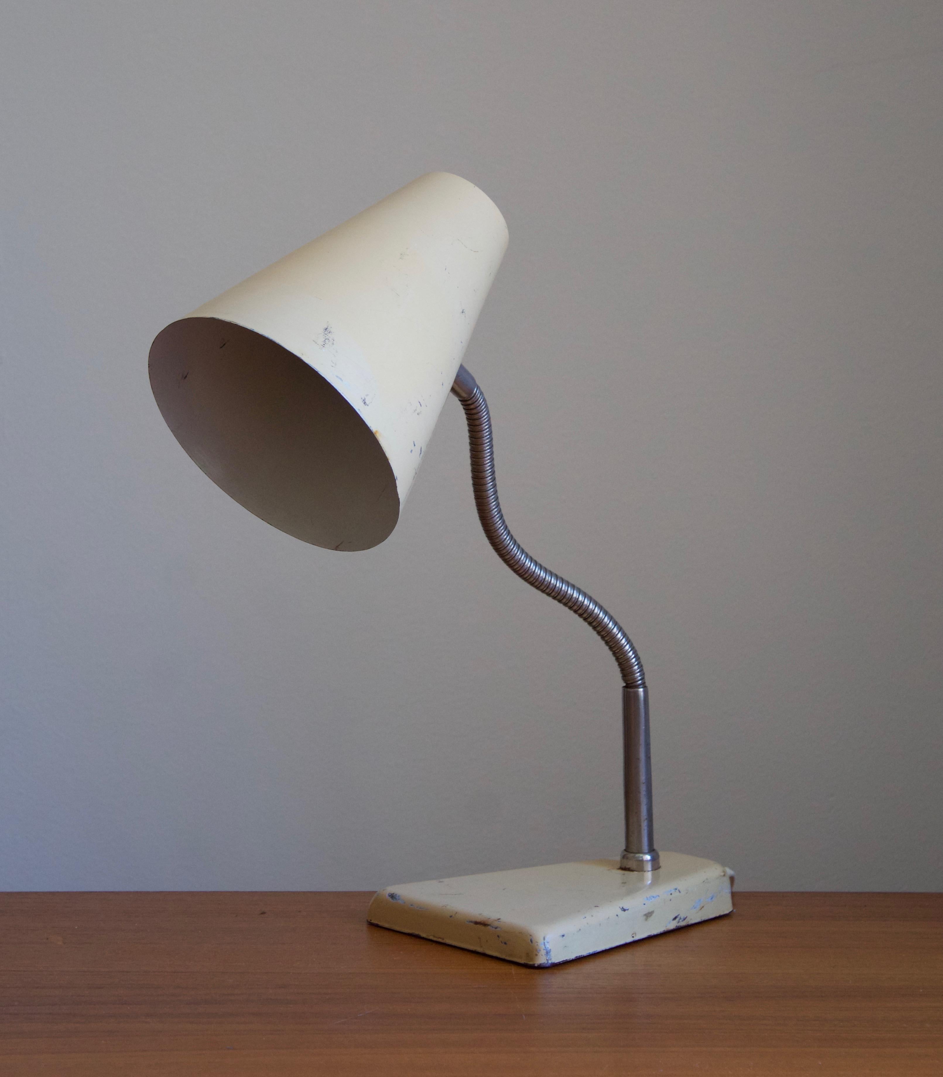An adjustable desk light. In lacquered metal and brass. Designed and produced in Denmark, 1950s.