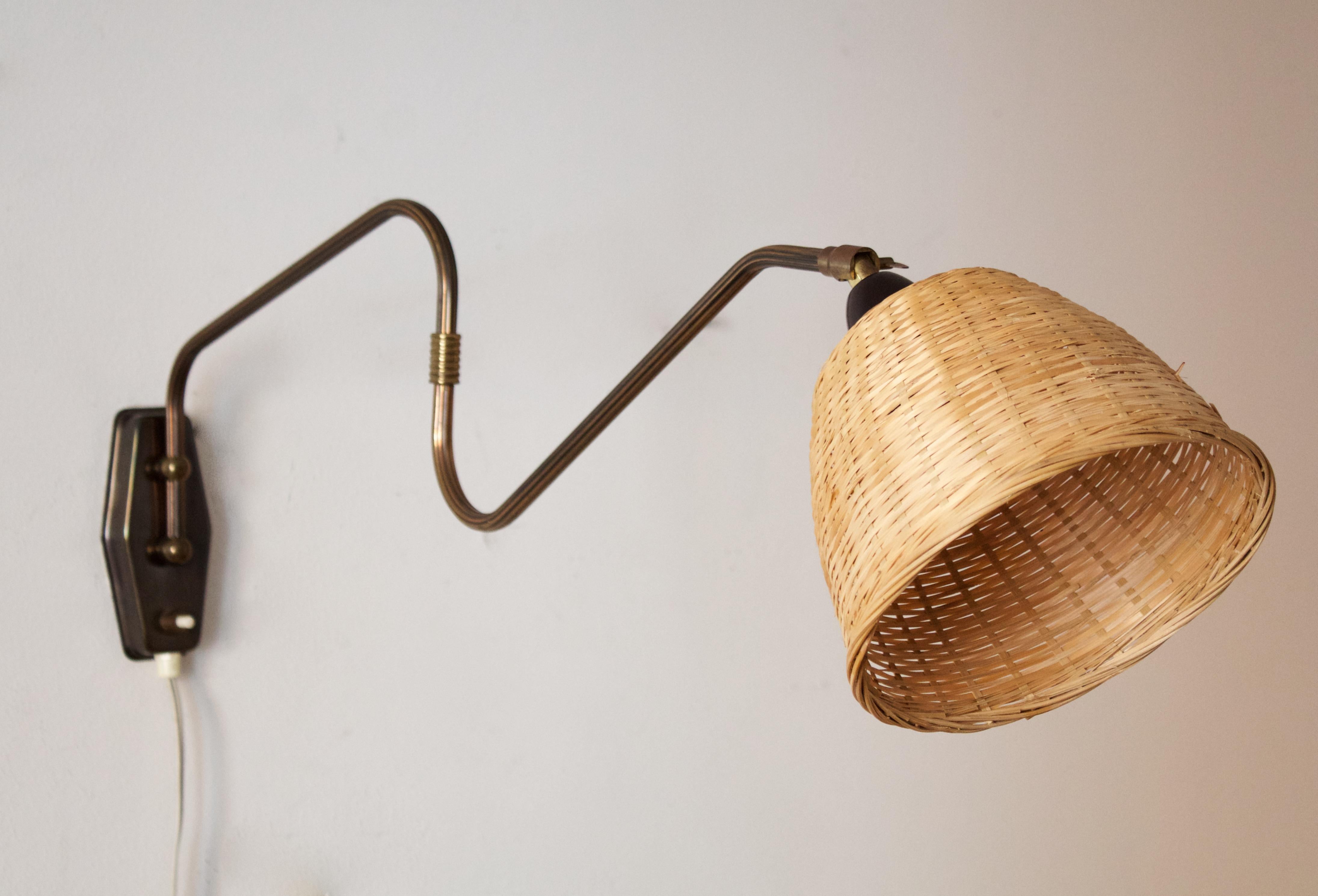 A small functionalist wall light / task light, designed and produced in Denmark, 1940s. Features brass, metal. Assorted Vintage rattan lampshade.

Stated dimensions with lampshade attached as is illustrated in the primary image.