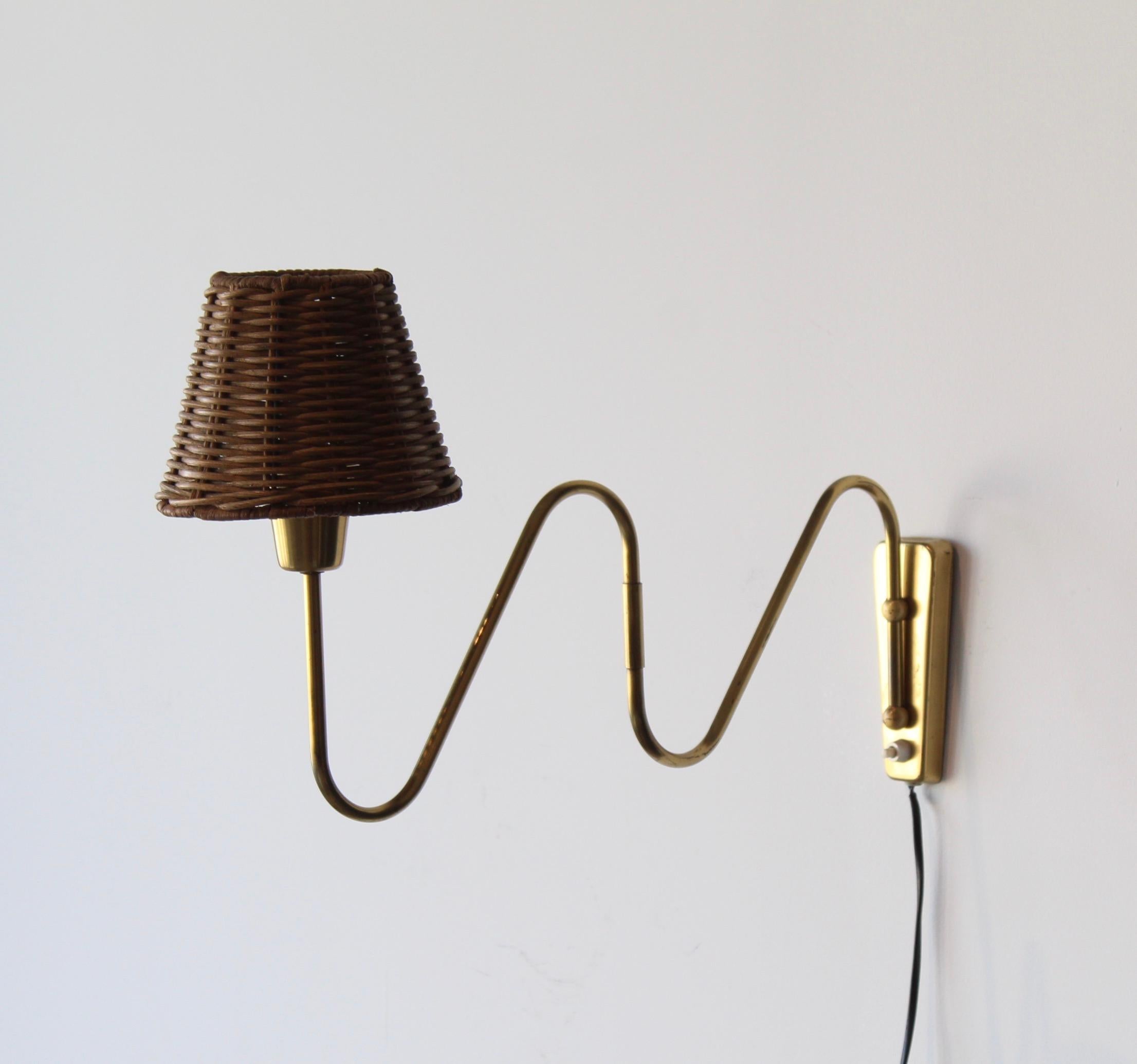 A functionalist wall light / task light, designed and produced in Denmark, 1940s. Features brass, metal. Assorted rattan lampshade.

Dimensions variable. Adjustable on joint attached directly to backplate, arm is fixed.