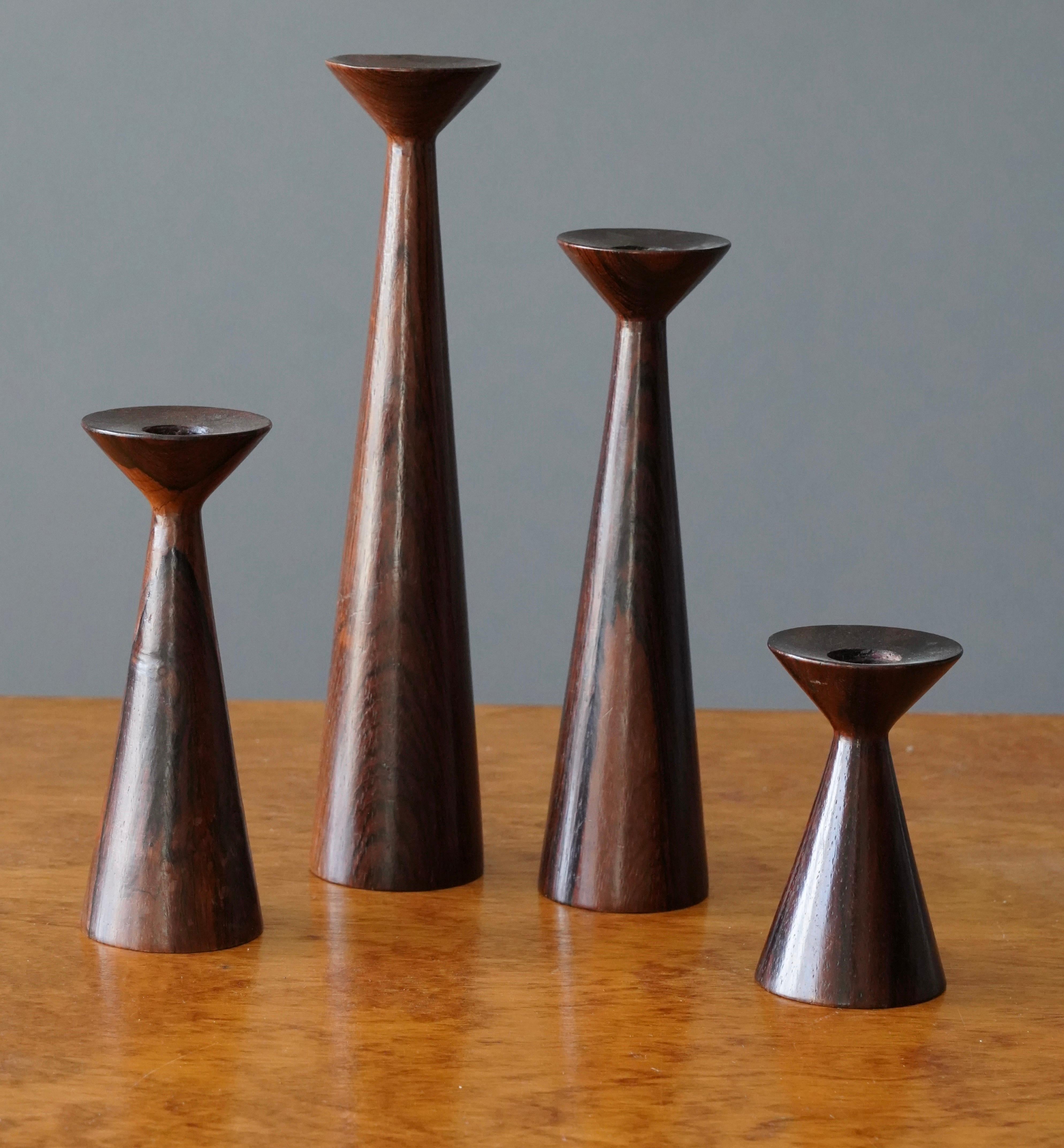 A set of four candlesticks, in solid turned rosewood.

Dimensions of each in decreasing order of height: 2.13 inches in diameter x 10 inches tall, 2.13 inches in diameter x 8 inches, 2.13 inches in diameter x 6 inches tall, 2.13 inches in diameter