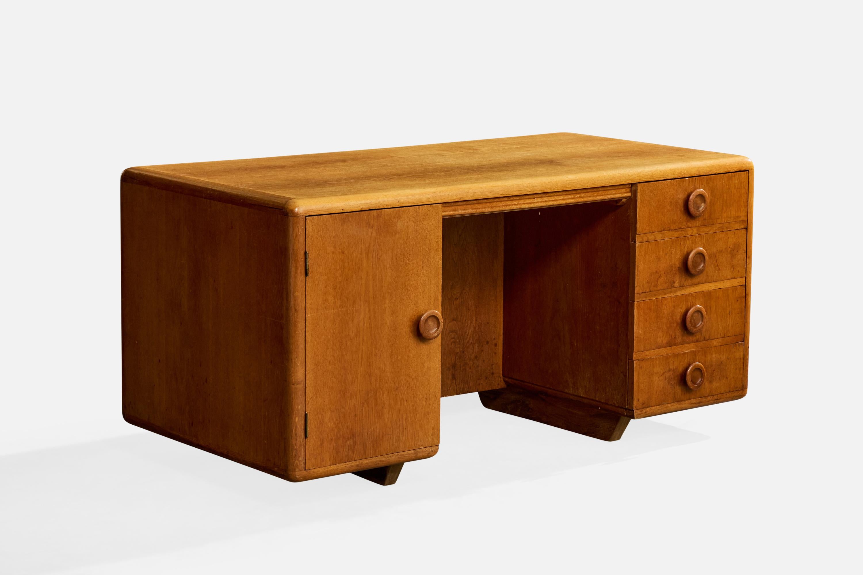 An oak desk designed and produced in Denmark, c. 1950s.

Minor to moderate wear to inside of drawers, tray, and cabinet.

Moderate wear and minor natural cracking to desktop surface and outer shelving.

Left side corner edge has larger crack (no