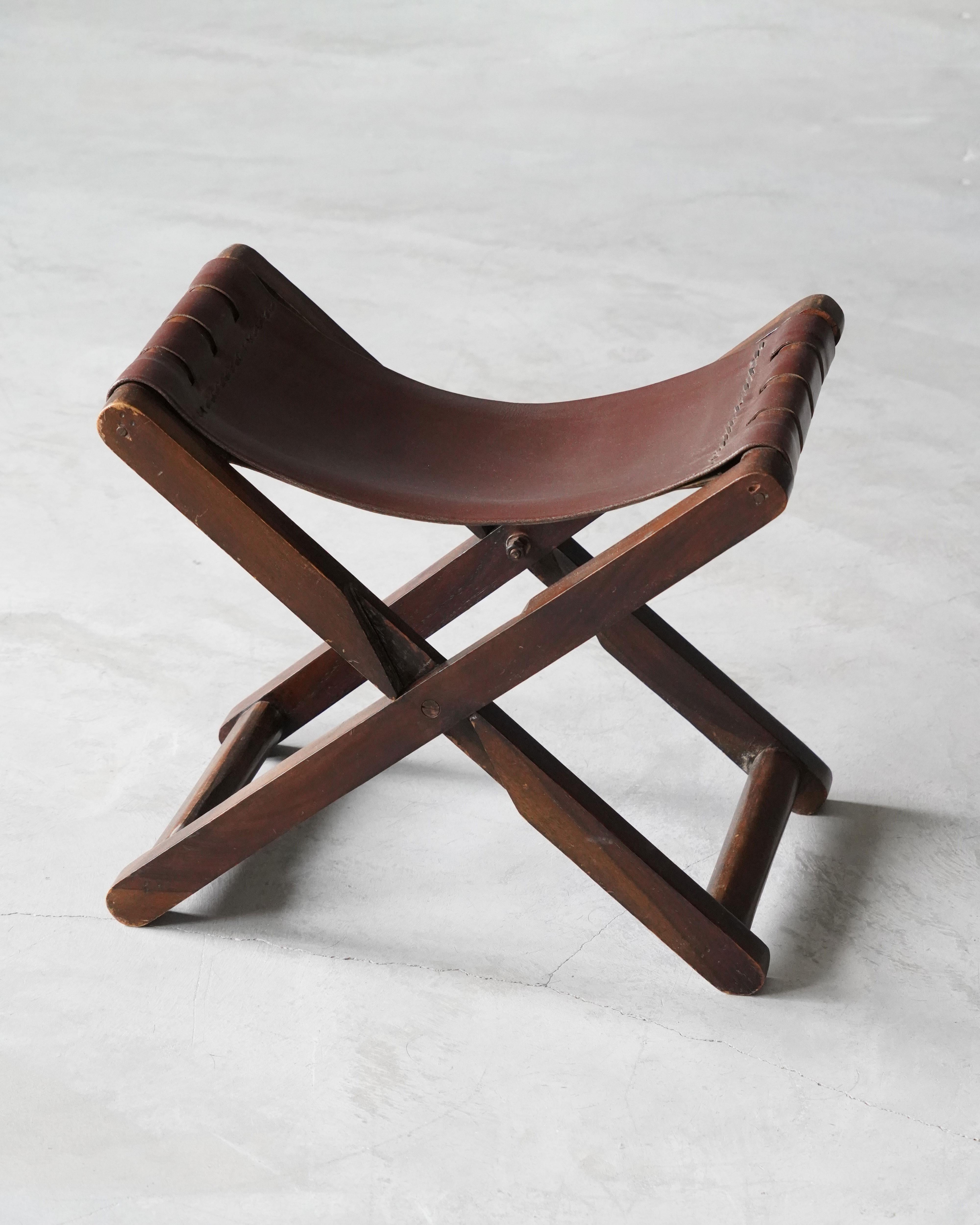 A foldable stool, designed and produced in Denmark, c. 1940s. Stained wood and original leather.