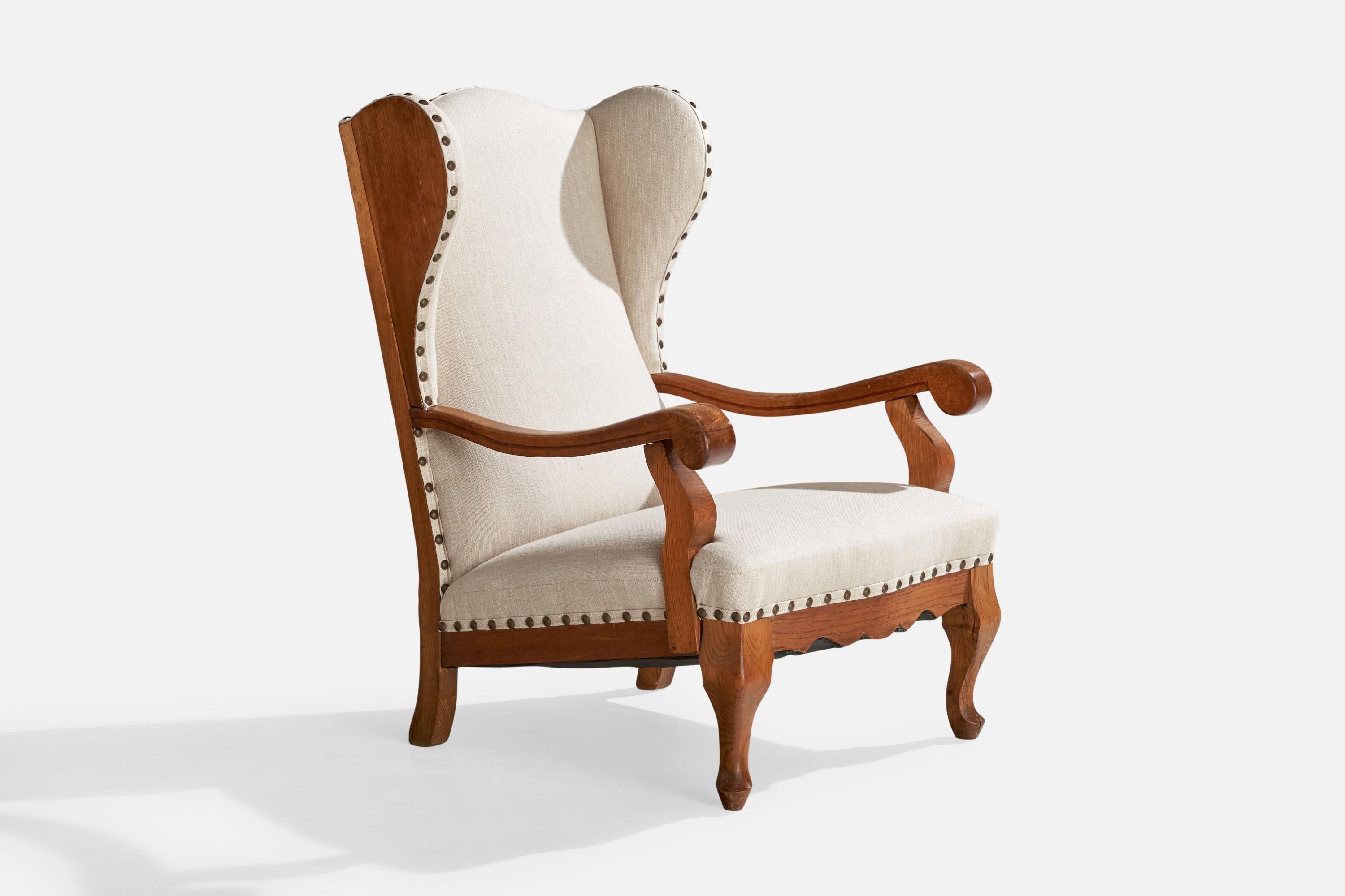 An oak, off white fabric and brass nail lounge chair designed and produced in Denmark, c. 1920s.

Dimensions: 41.2” H 29.25” W x 34” D