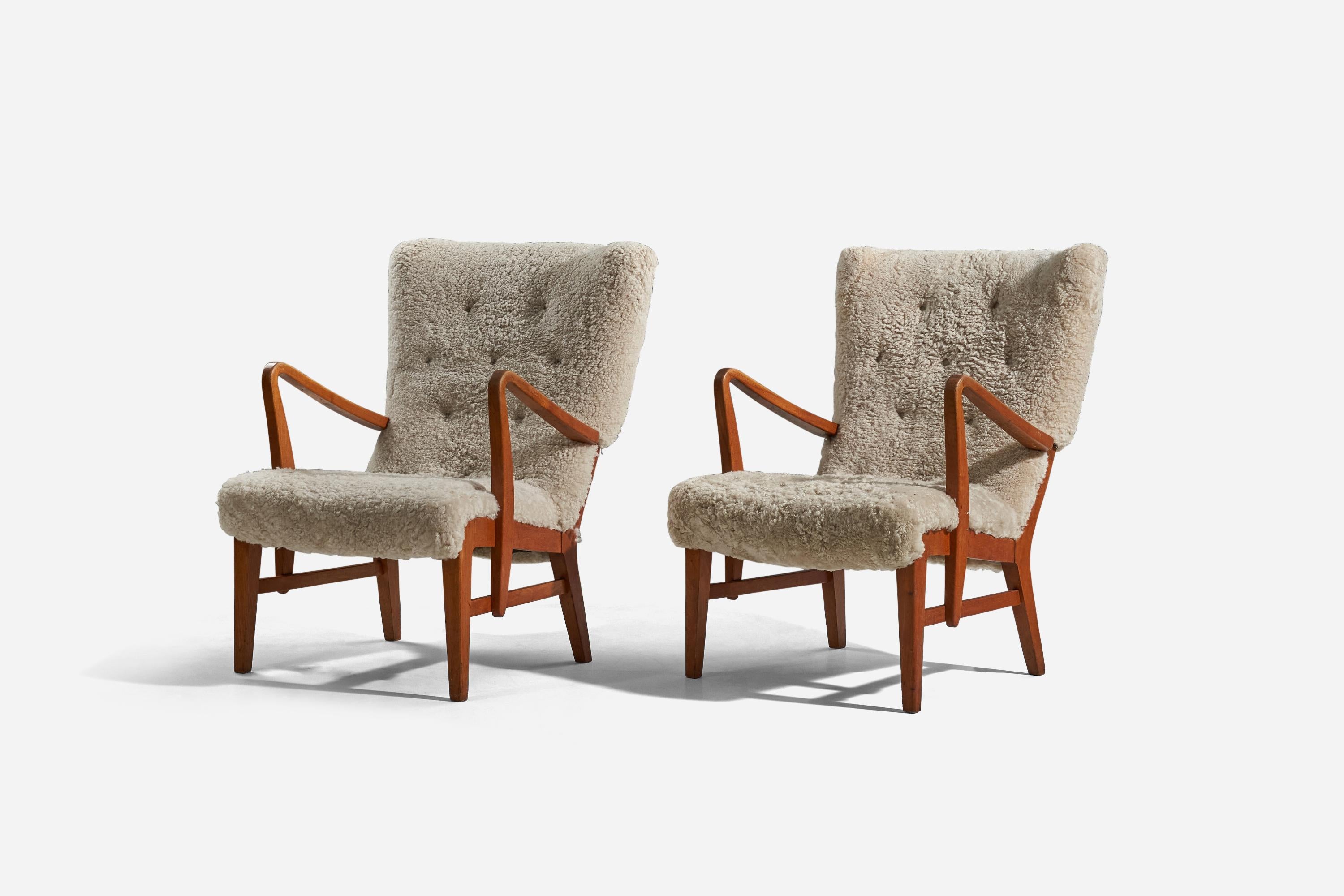 A pair of sheepskin and wood lounge chairs designed and produced in Denmark, 1940s. 