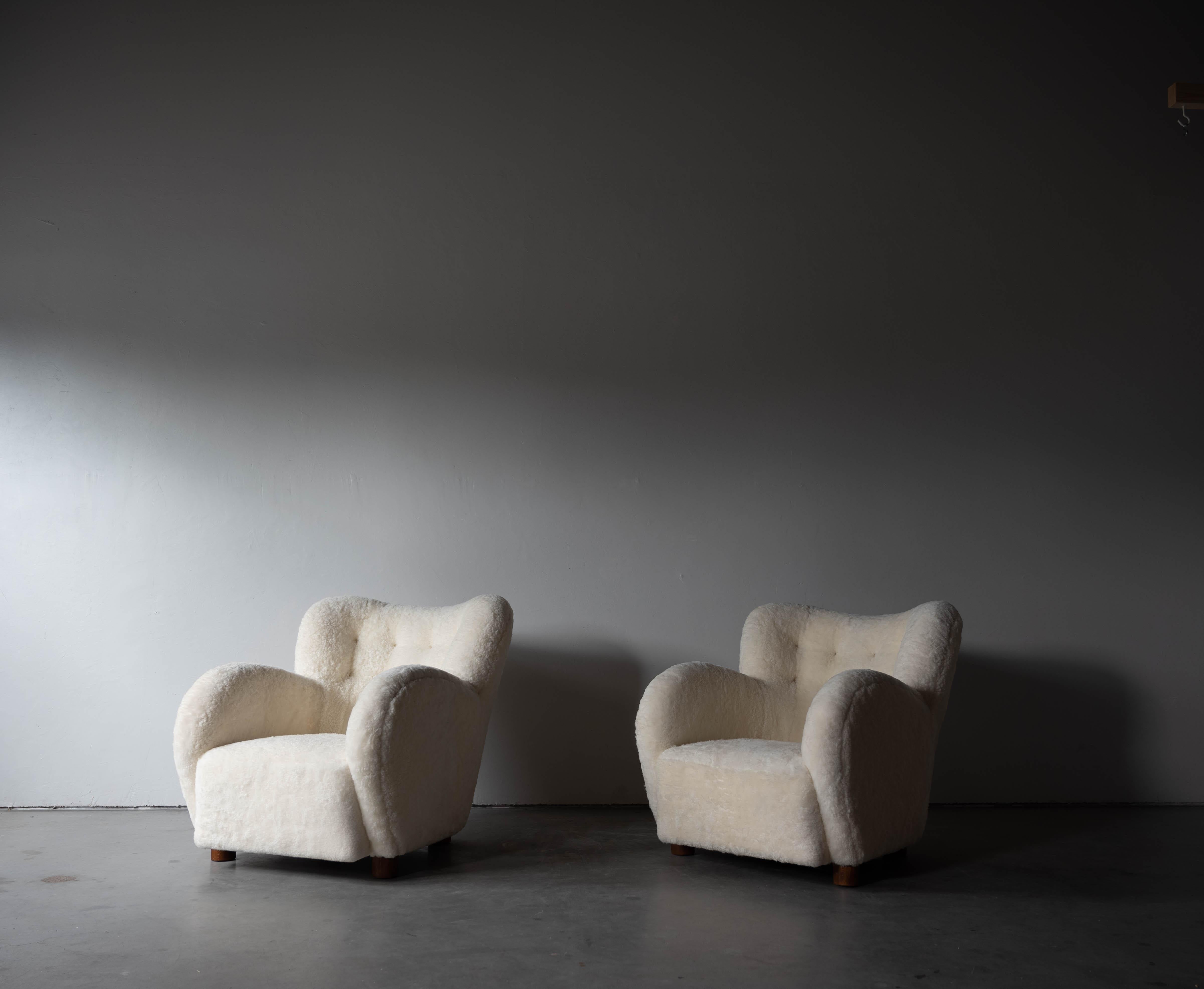 A pair of sheepskin and wood lounge chairs designed and produced in Denmark, 1940s.