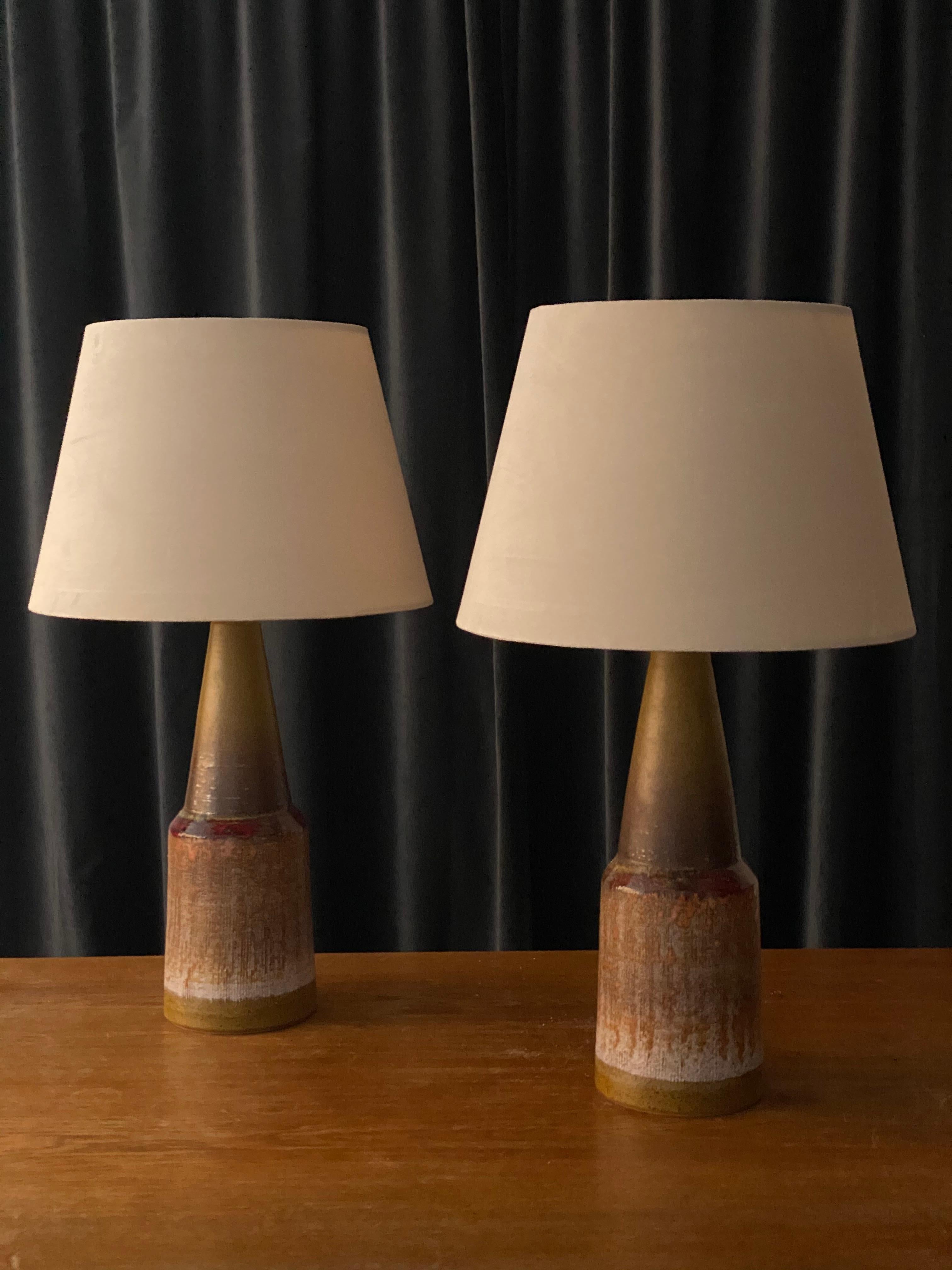 A pair of highly sculptural and sizable stoneware lamps. Features a highly artistic beige / brown / grey / red glaze. Marked 