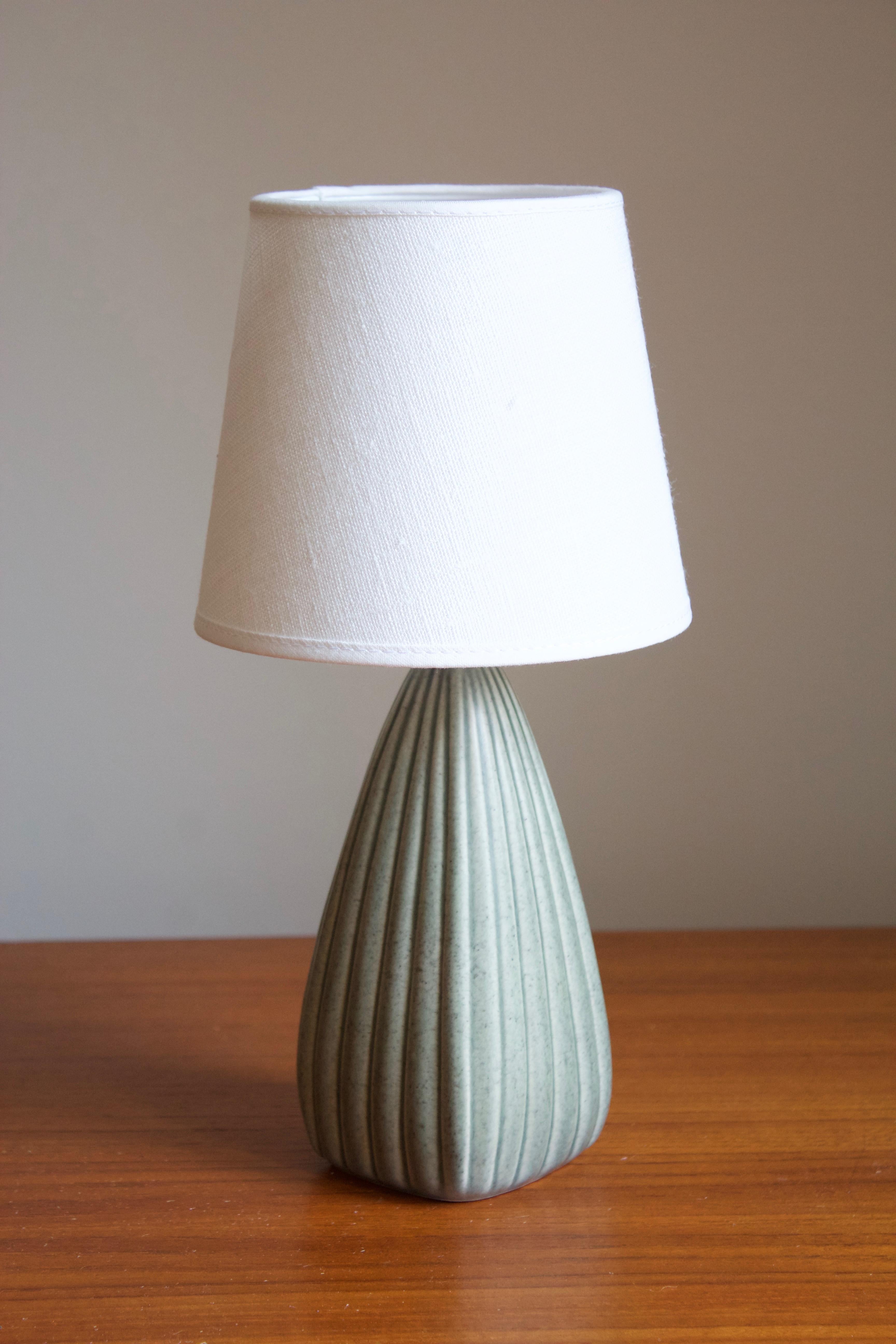 A small table lamp. Signed. Designed and produced in Denmark, 1960s-1970s. Unidentified designer and maker. Brand new high-end linen lampshade. Features simple ribbed ornamentation typical to Danish ceramics. Sold without lampshade.

Other designers