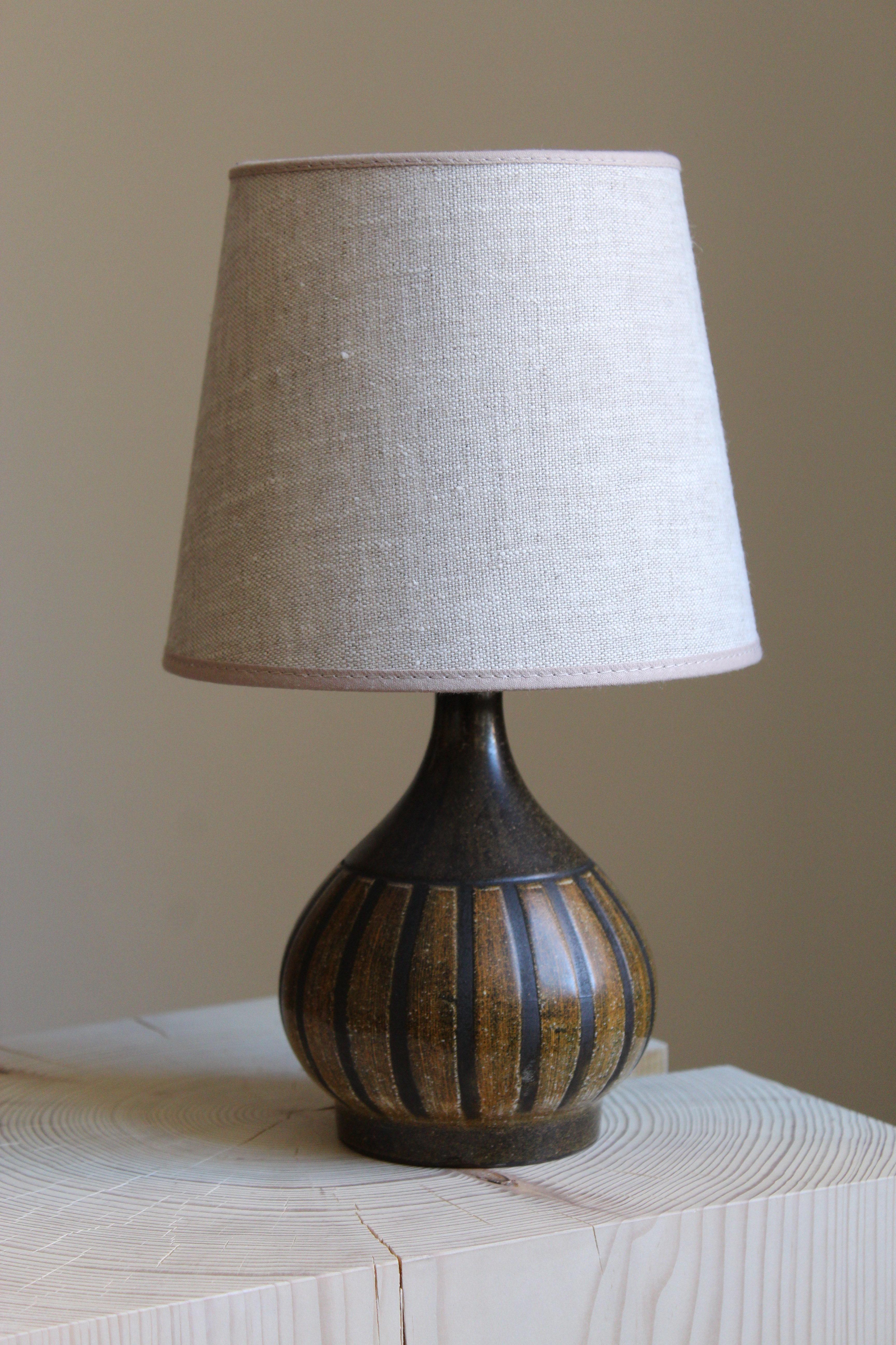 A small table lamp. Signed. Designed and produced in Denmark, 1960s. Unidentified designer and maker. Sold without lampshade.

Glaze features brown-black colors.